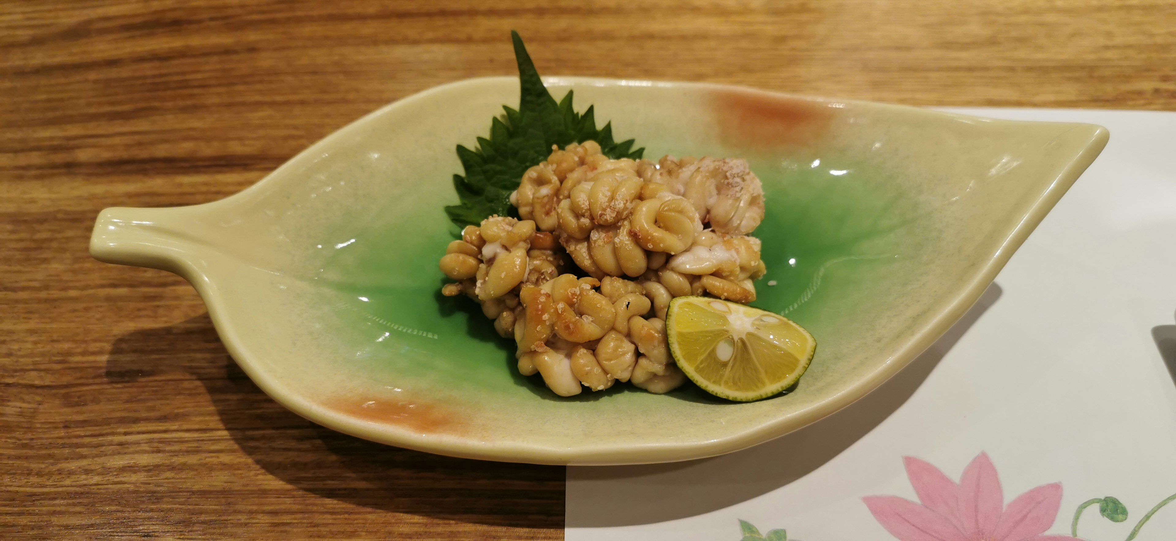 Plat servi sur une assiette en forme de feuille verte avec du poulet et une tranche de citron vert