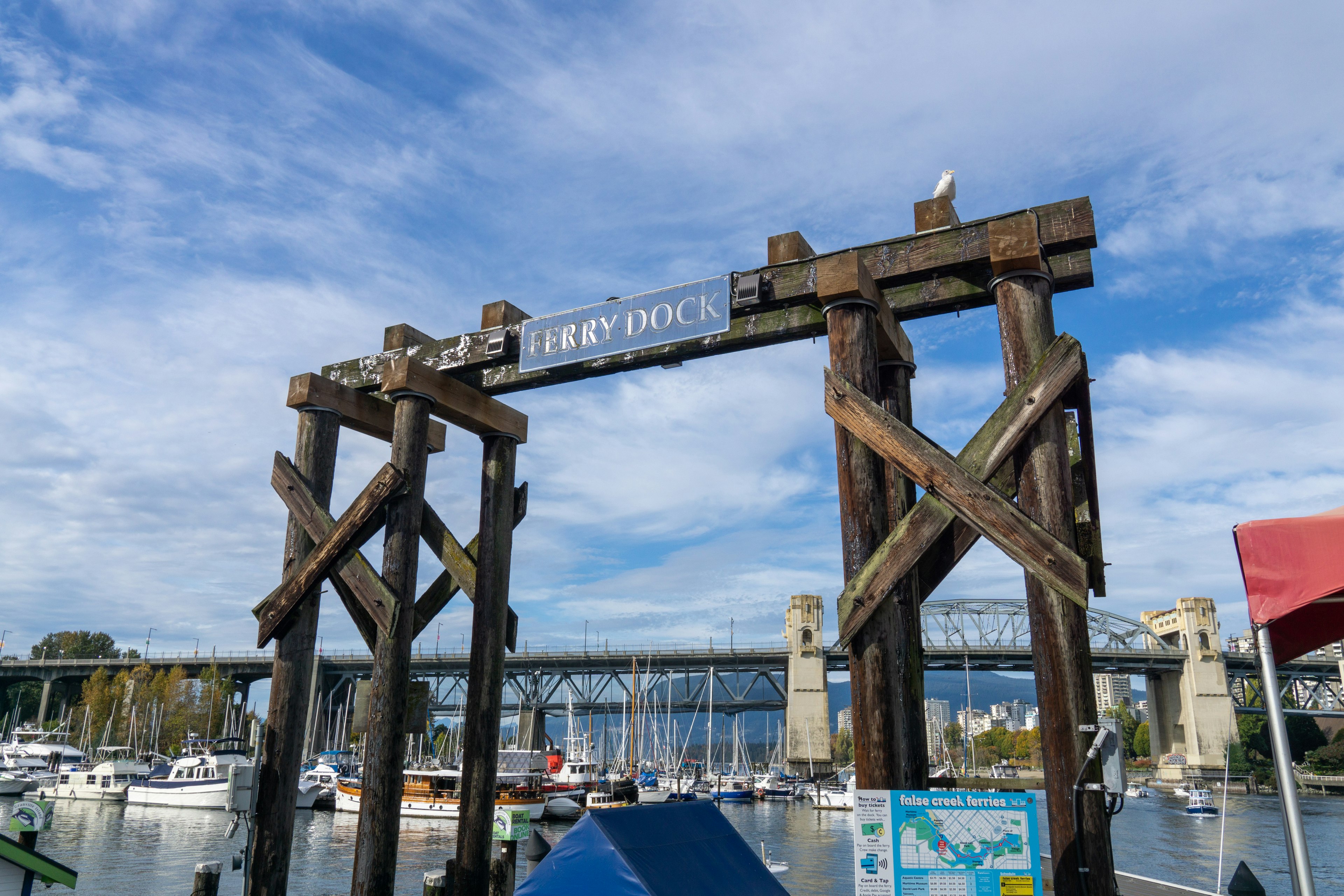 Entrée d'un quai en bois avec un panneau 'FISH DOCK' et des bateaux environnants