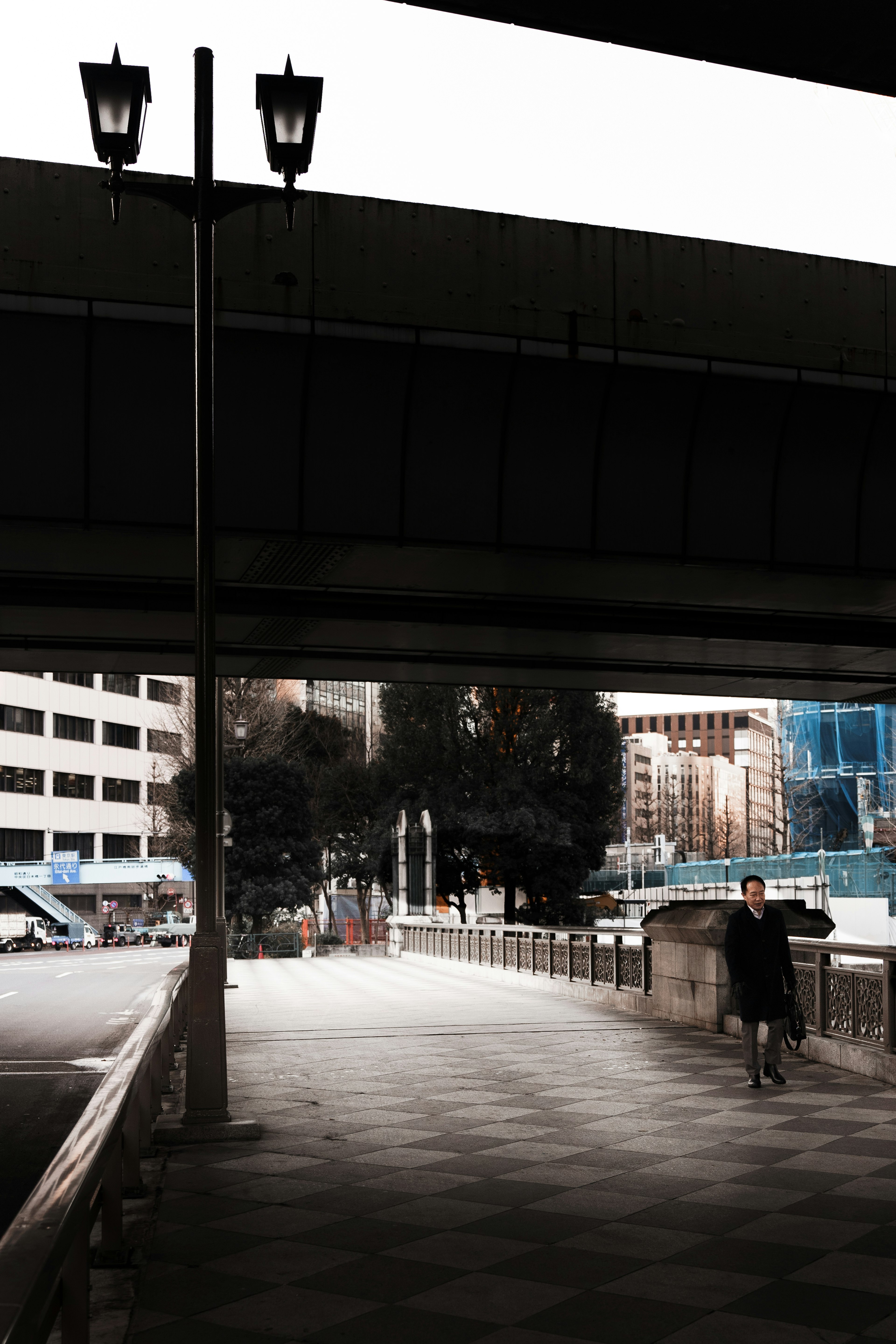 Urban scene with a pedestrian on the sidewalk under a bridge