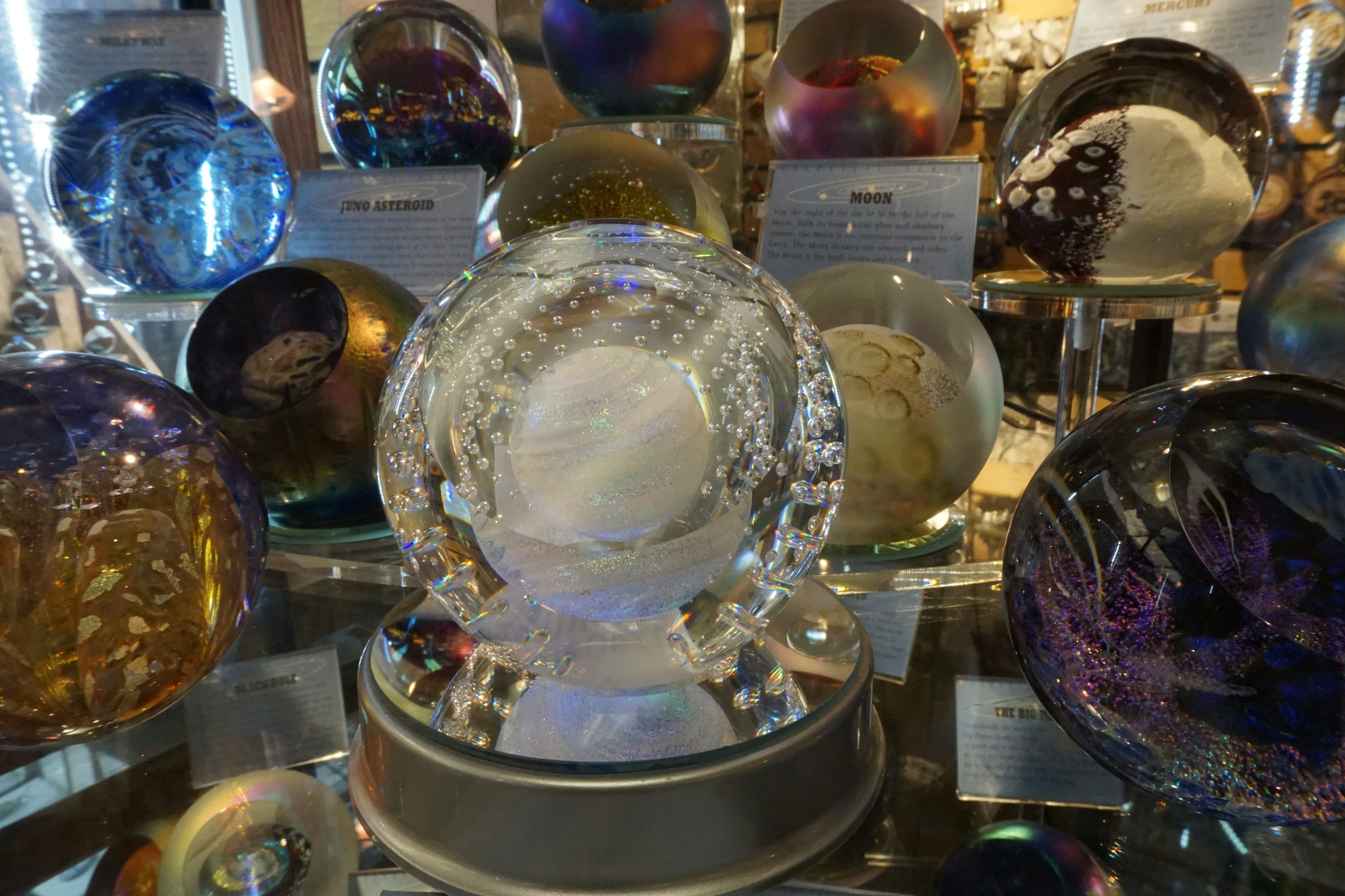 A clear crystal ball placed in the center of colorful crystal balls in a display space