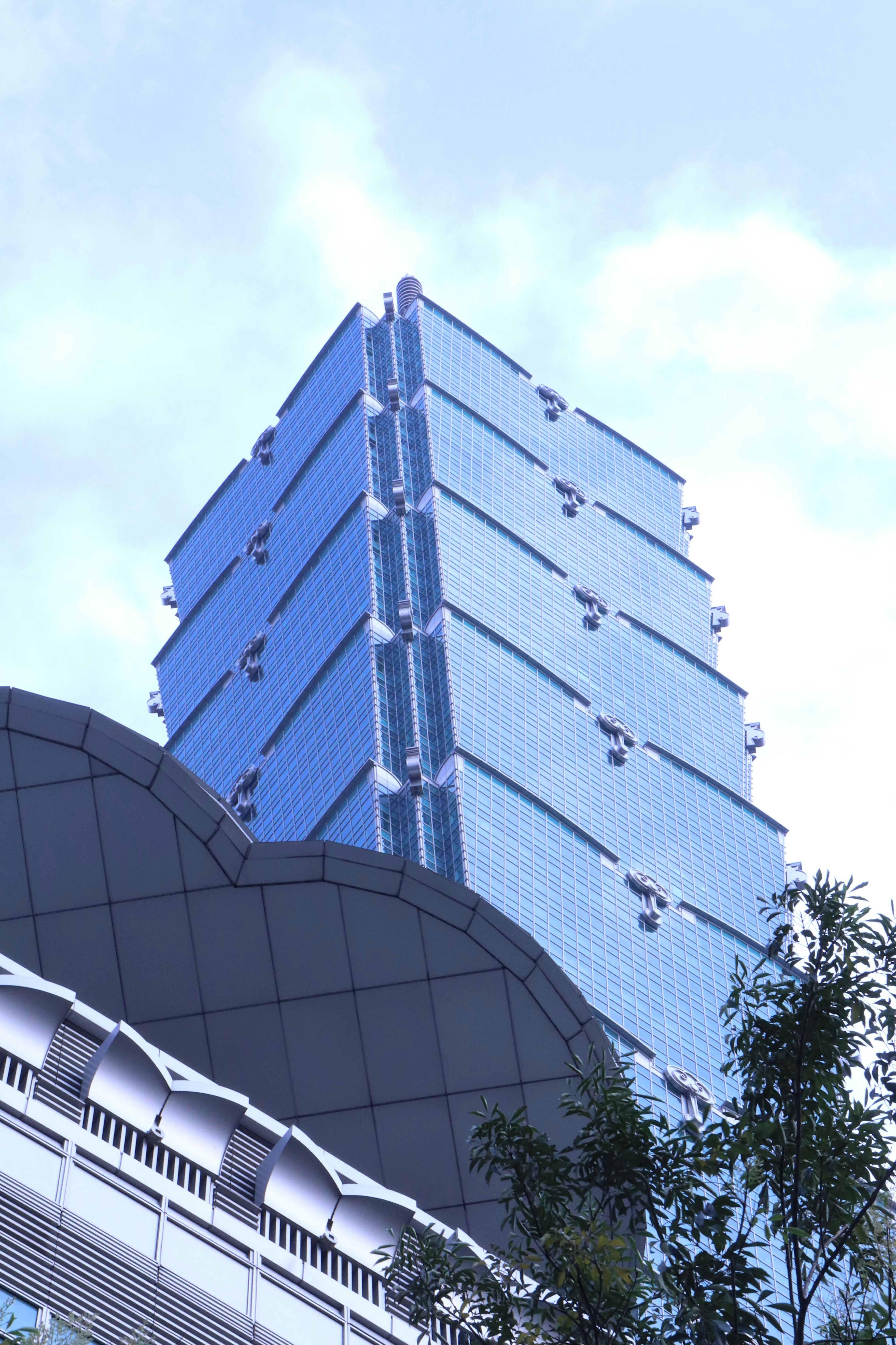 The upper part of a blue glass skyscraper rises towards the sky