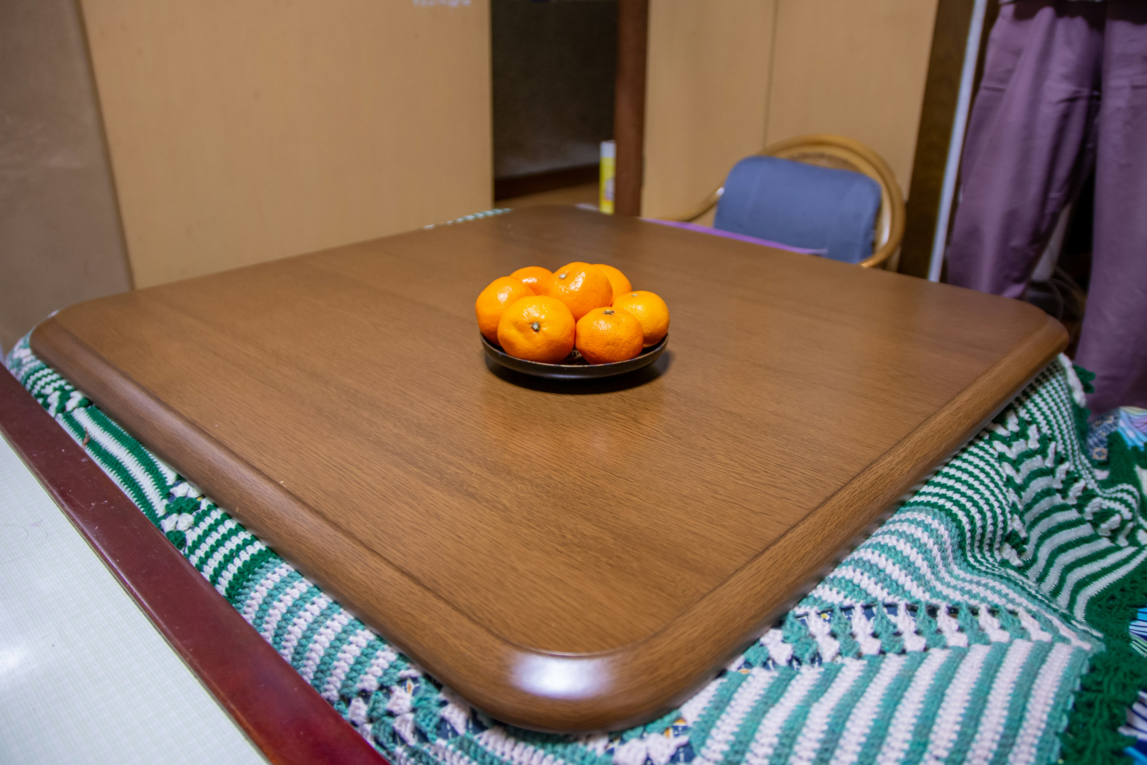 A wooden table with a plate of oranges in the center