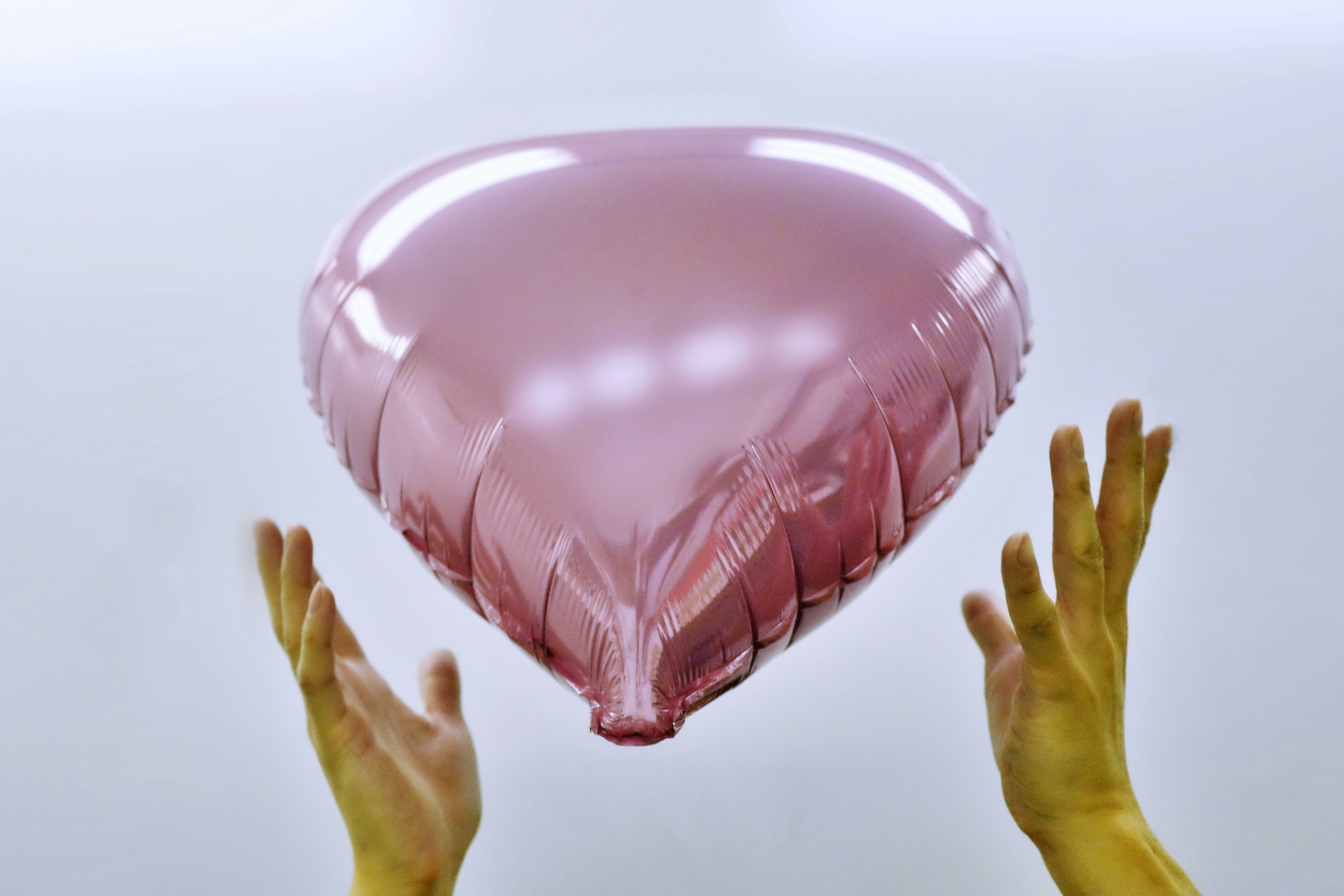 Mani che tengono un palloncino a forma di cuore rosa