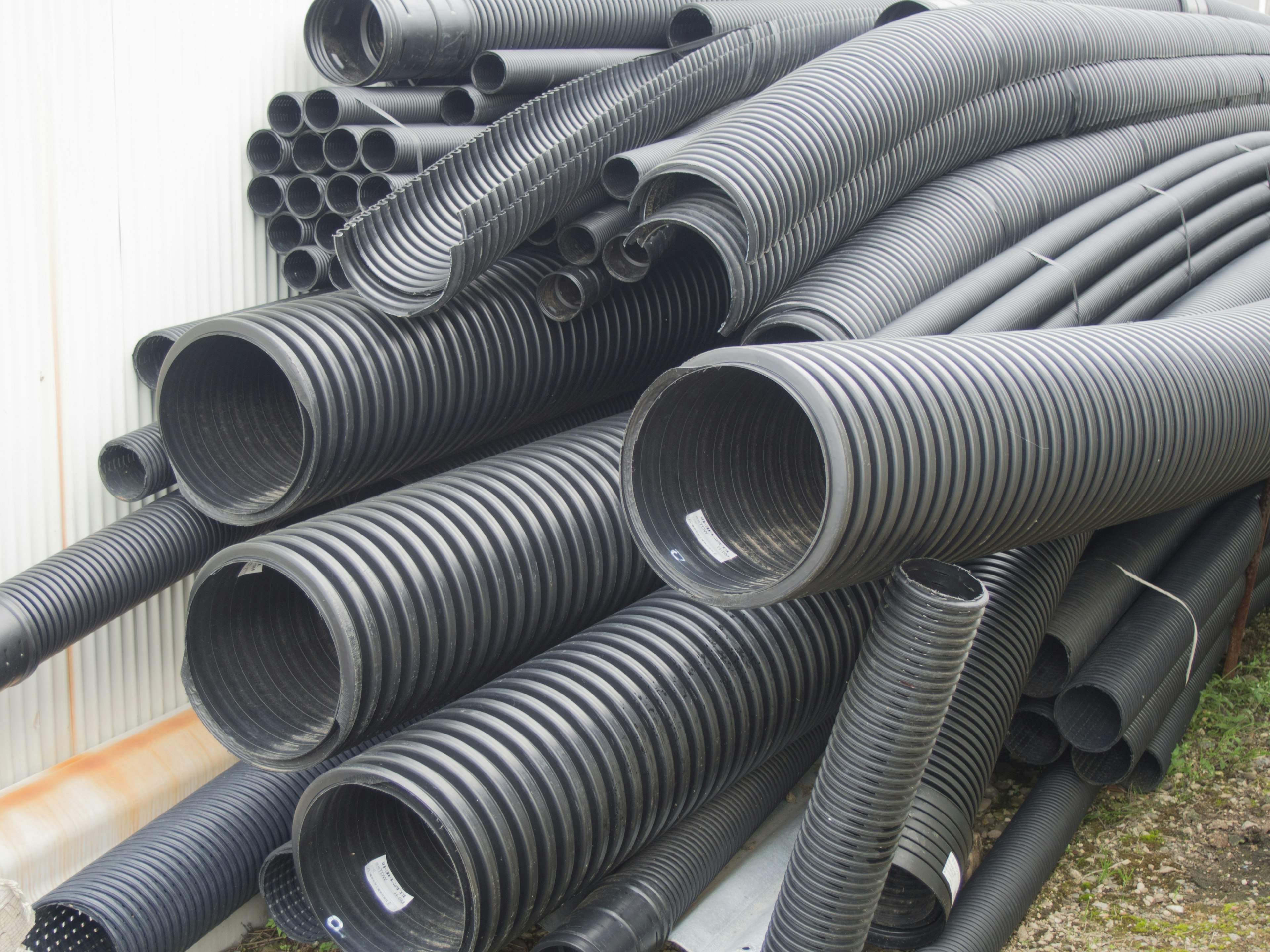 A collection of stacked black pipes in an industrial setting