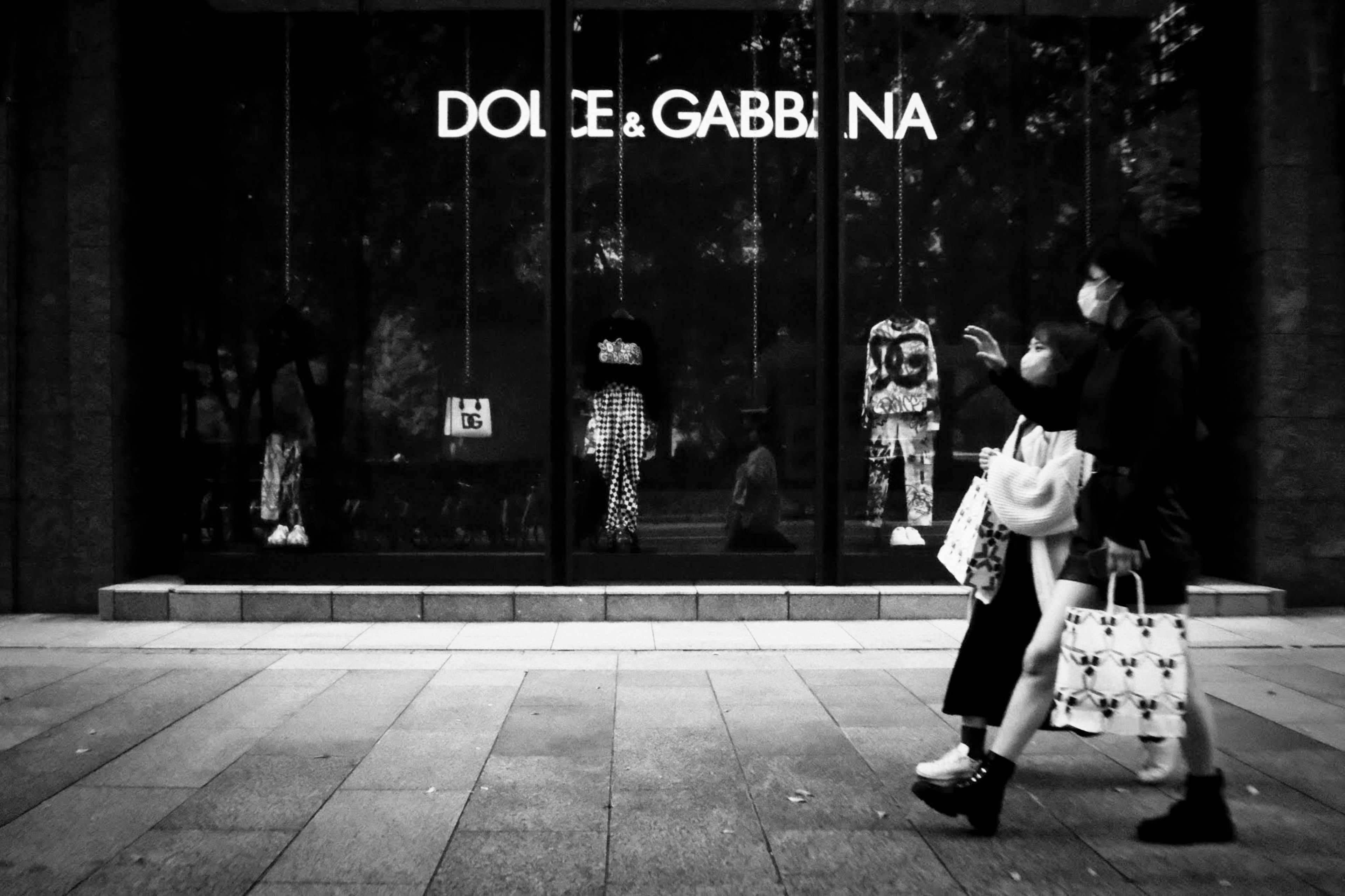 兩名女性在Dolce & Gabbana商店前走的黑白照片