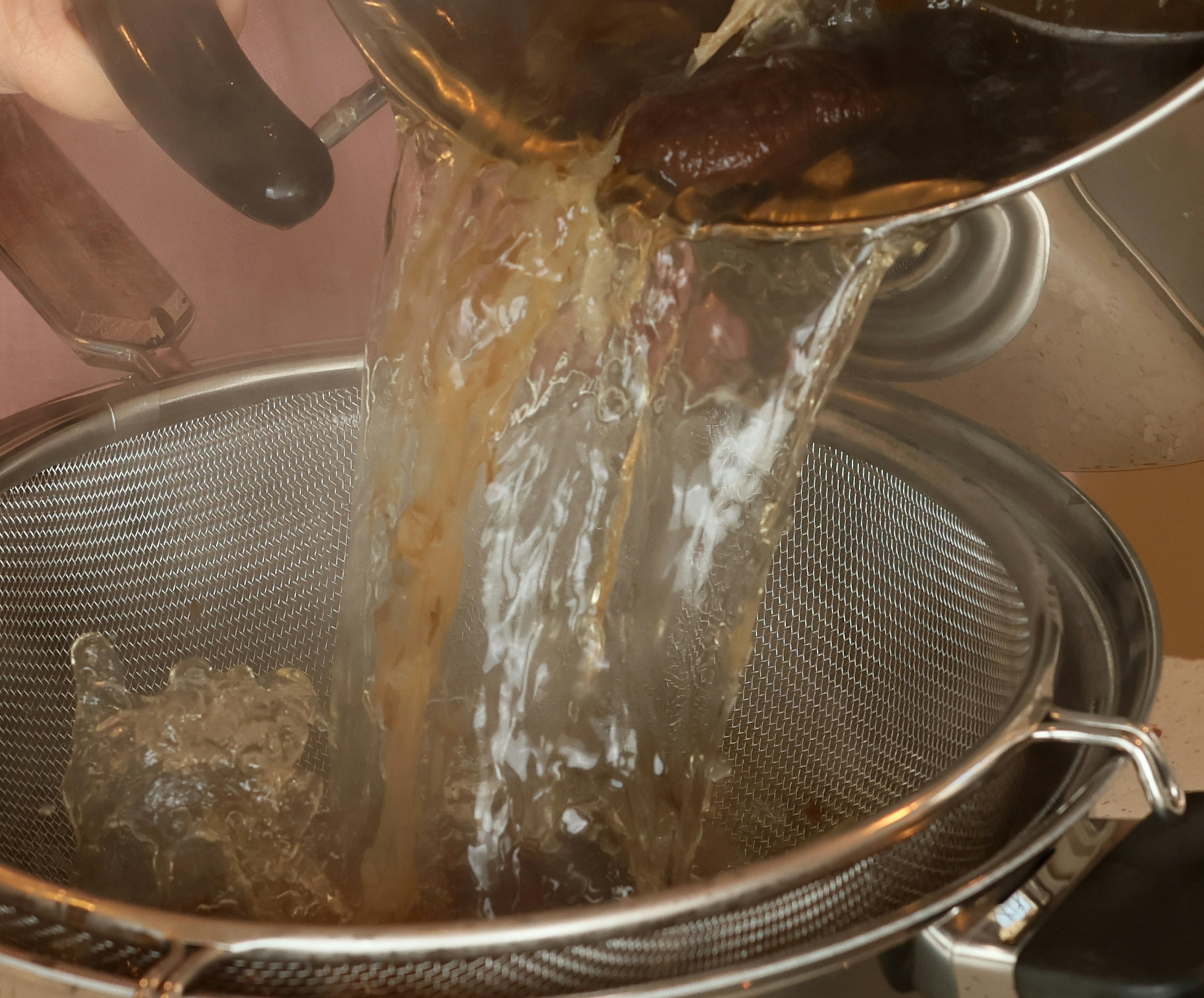 Hot liquid pouring from a pot into a strainer