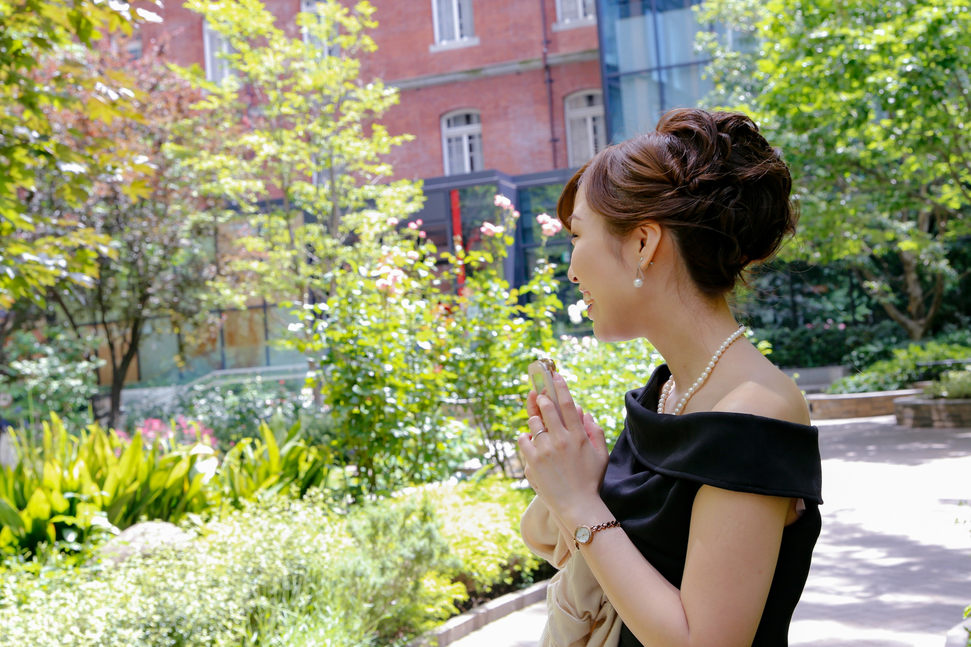 Profil latéral d'une femme avec les mains jointes dans un parc entouré de verdure et de fleurs