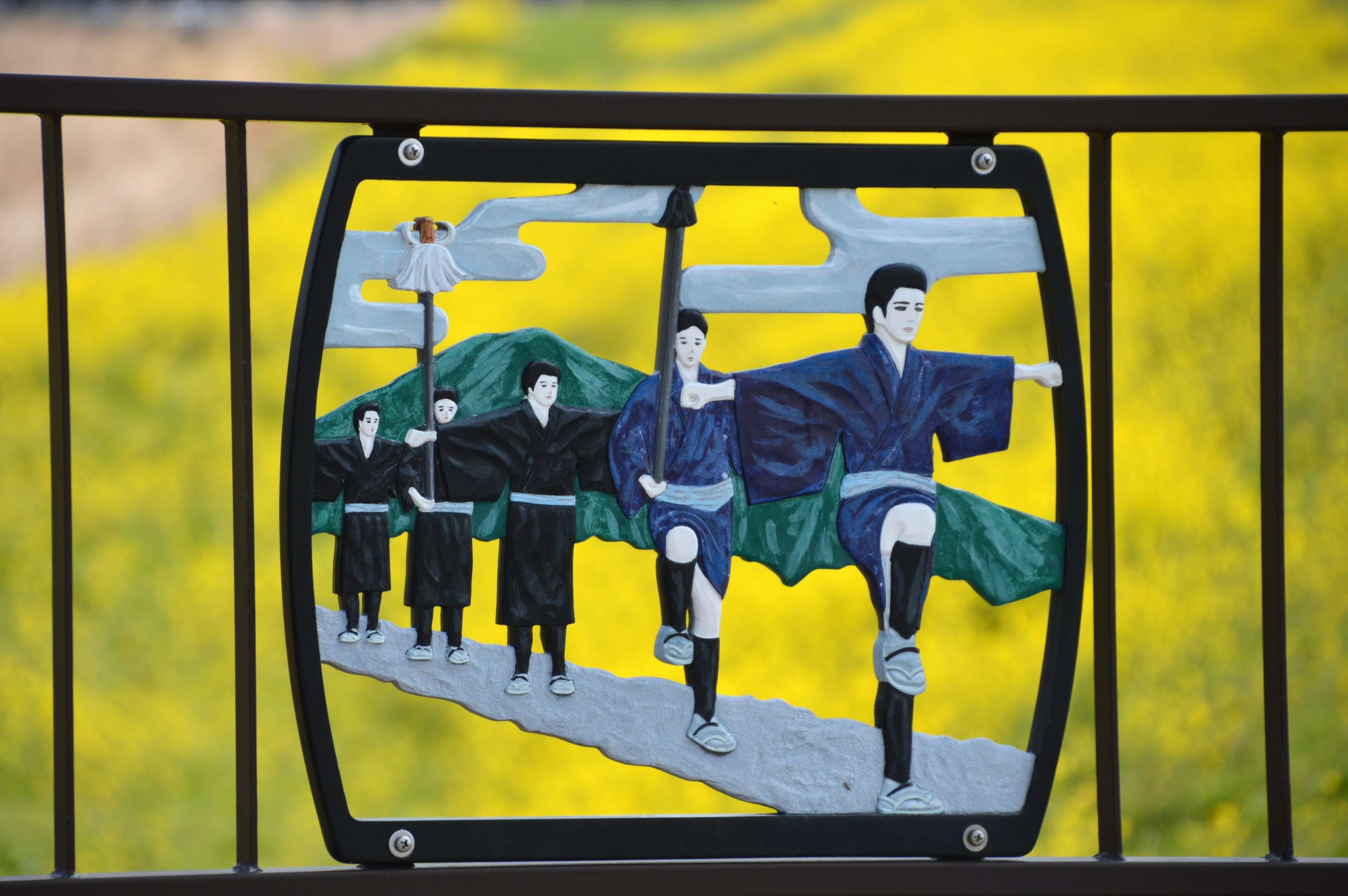 Art featuring men in blue kimonos marching against a vibrant yellow background