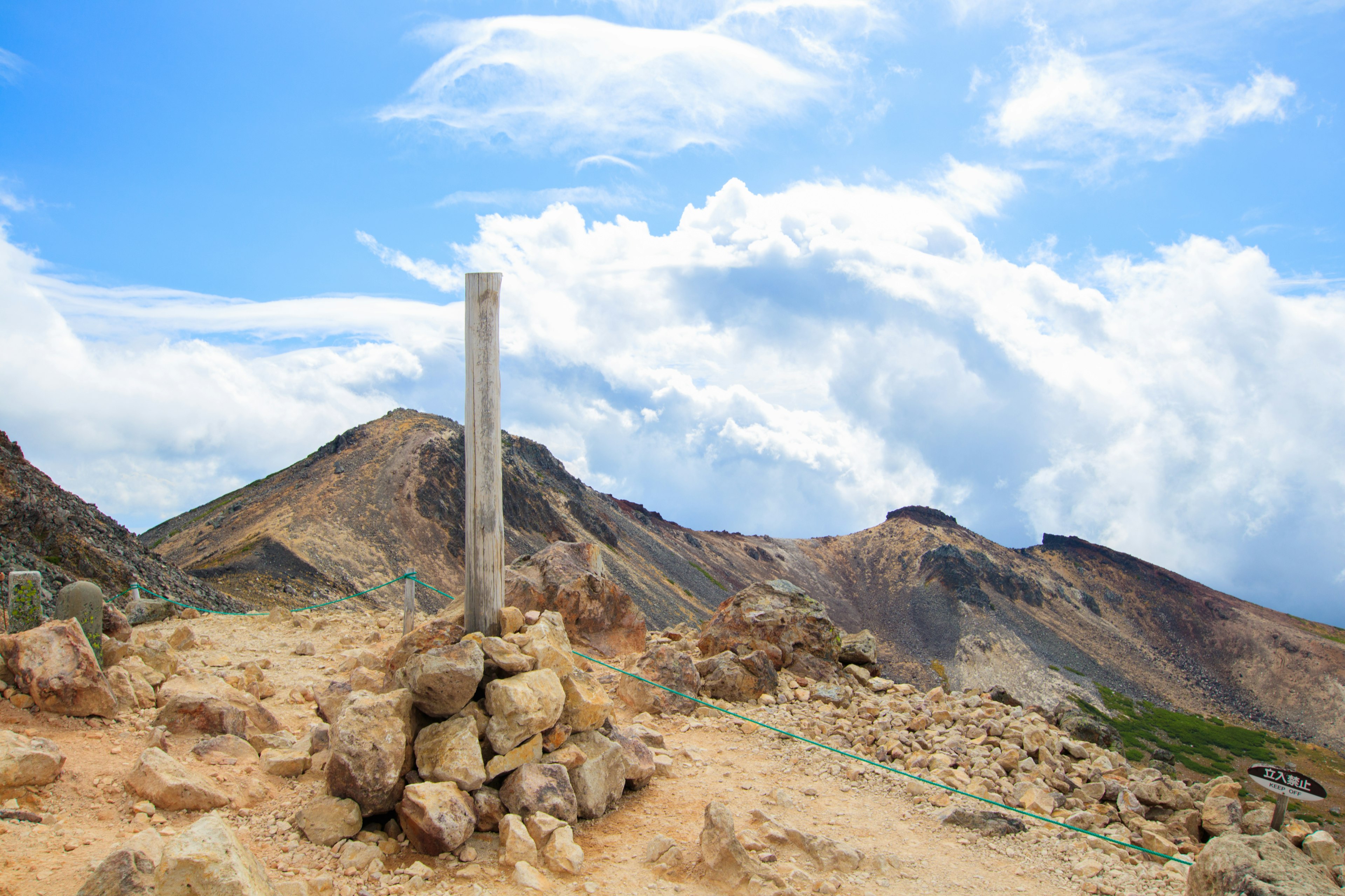 Puncak gunung dengan papan petunjuk dan tumpukan batu