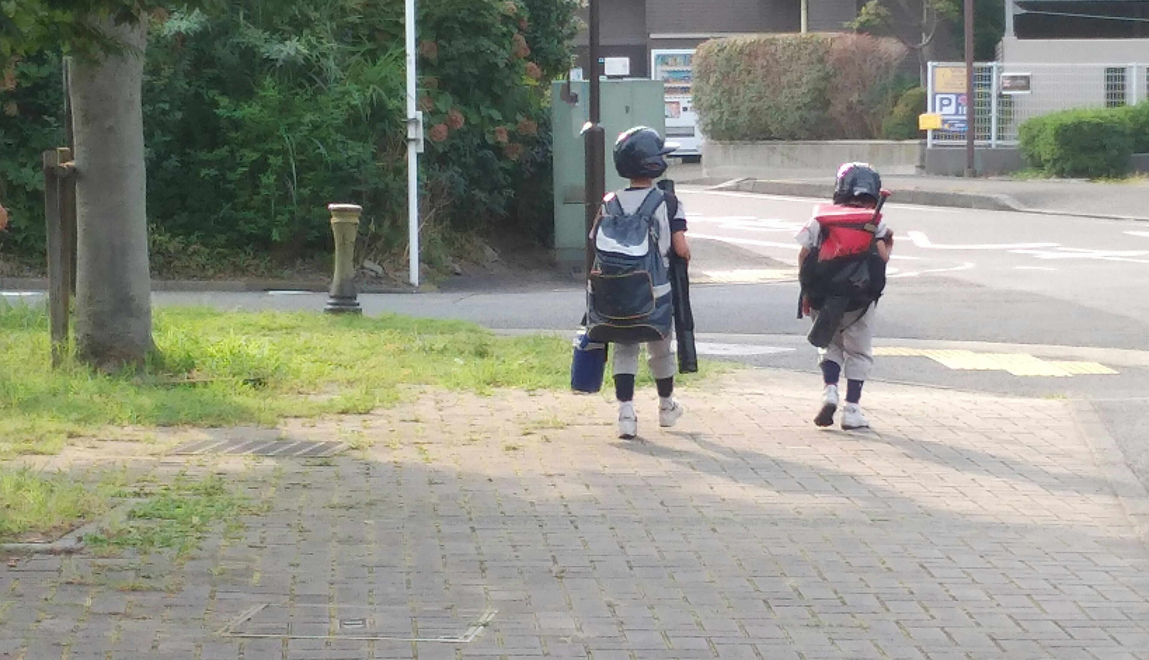 Two children walking to school carrying backpacks on a sunny day