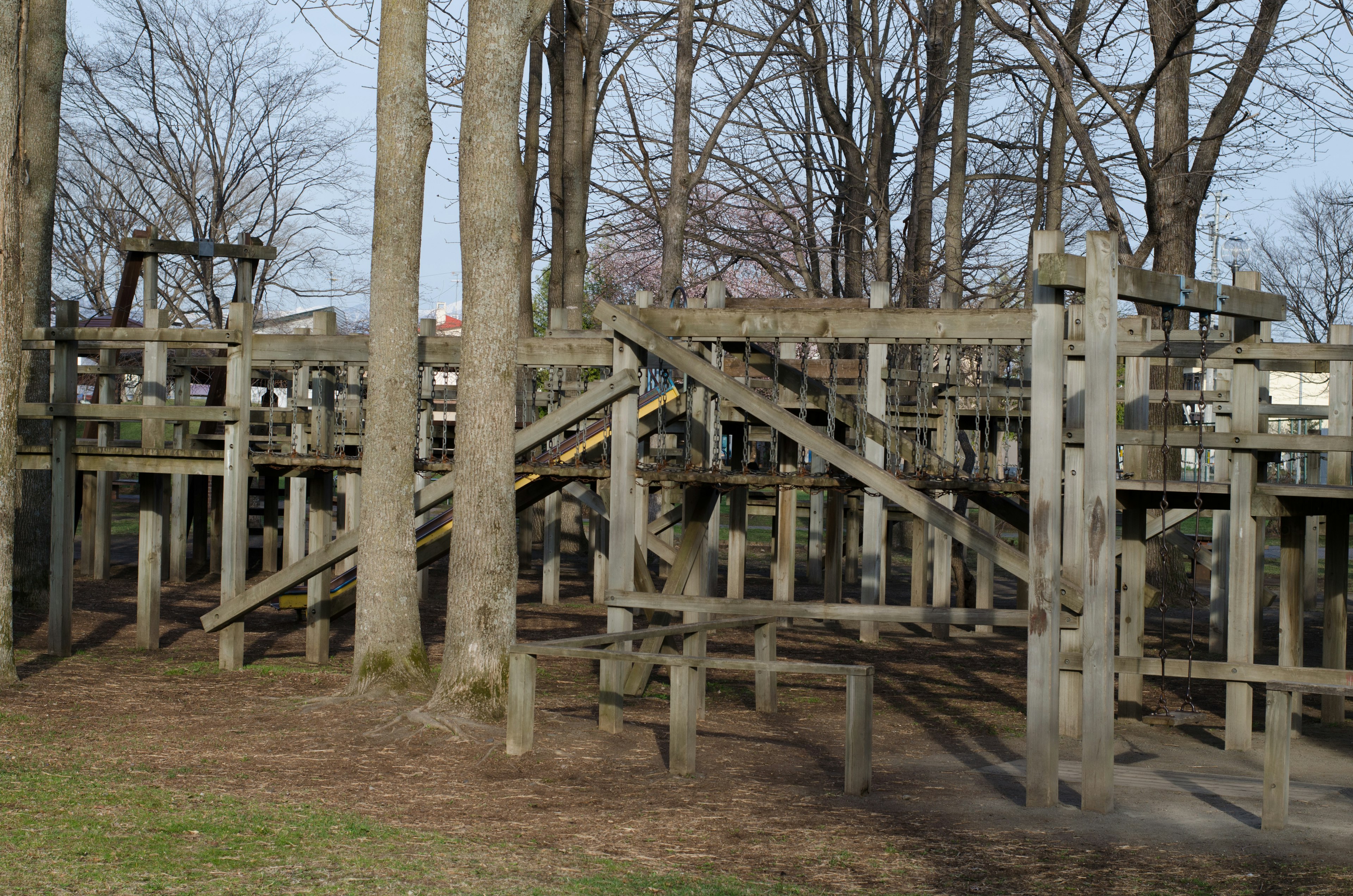 木製の遊具がある公園の一部や樹木の間に広がる構造物