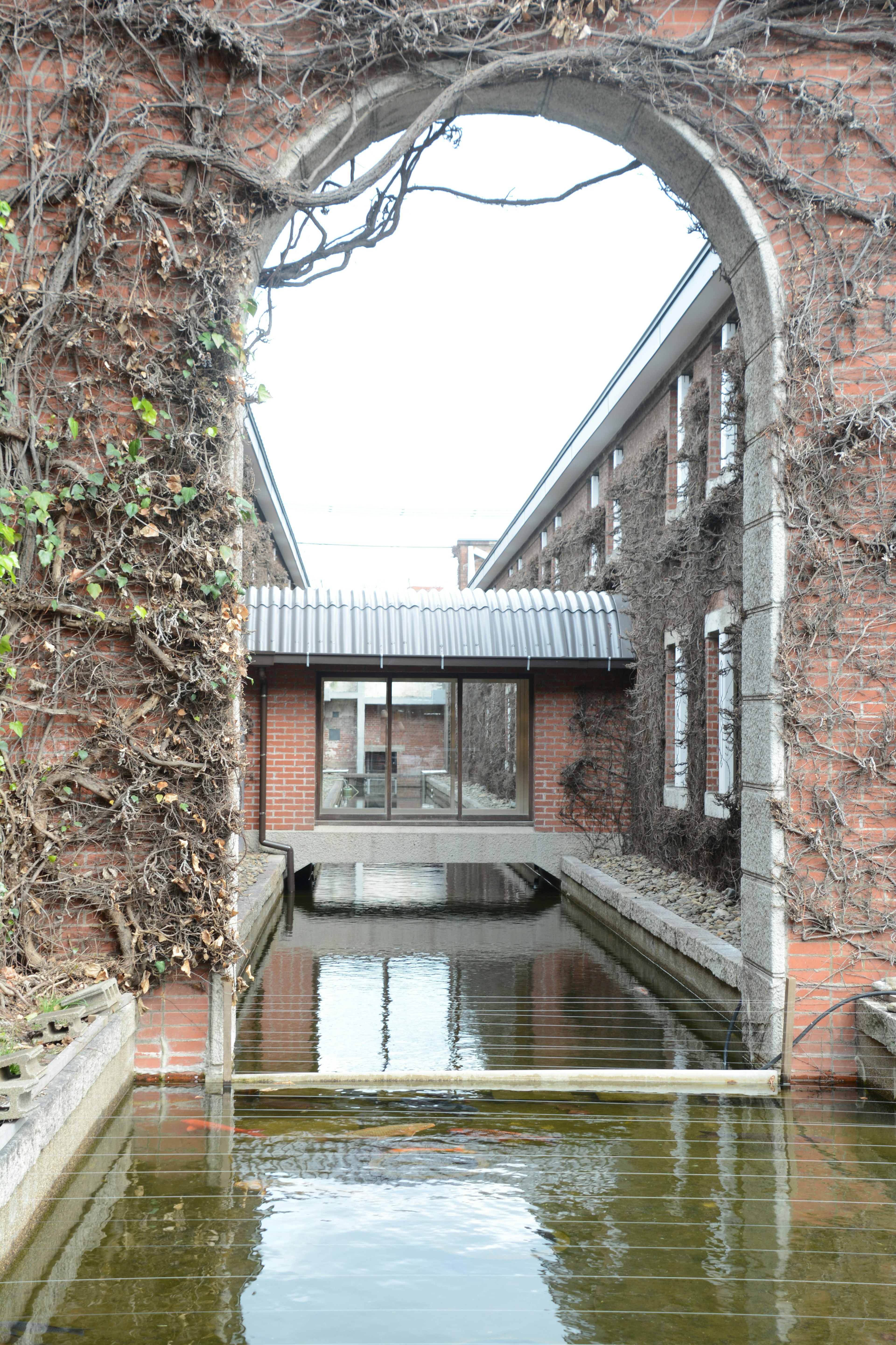 煉瓦でできたアーチの向こう側に水を含む運河と建物が見える風景