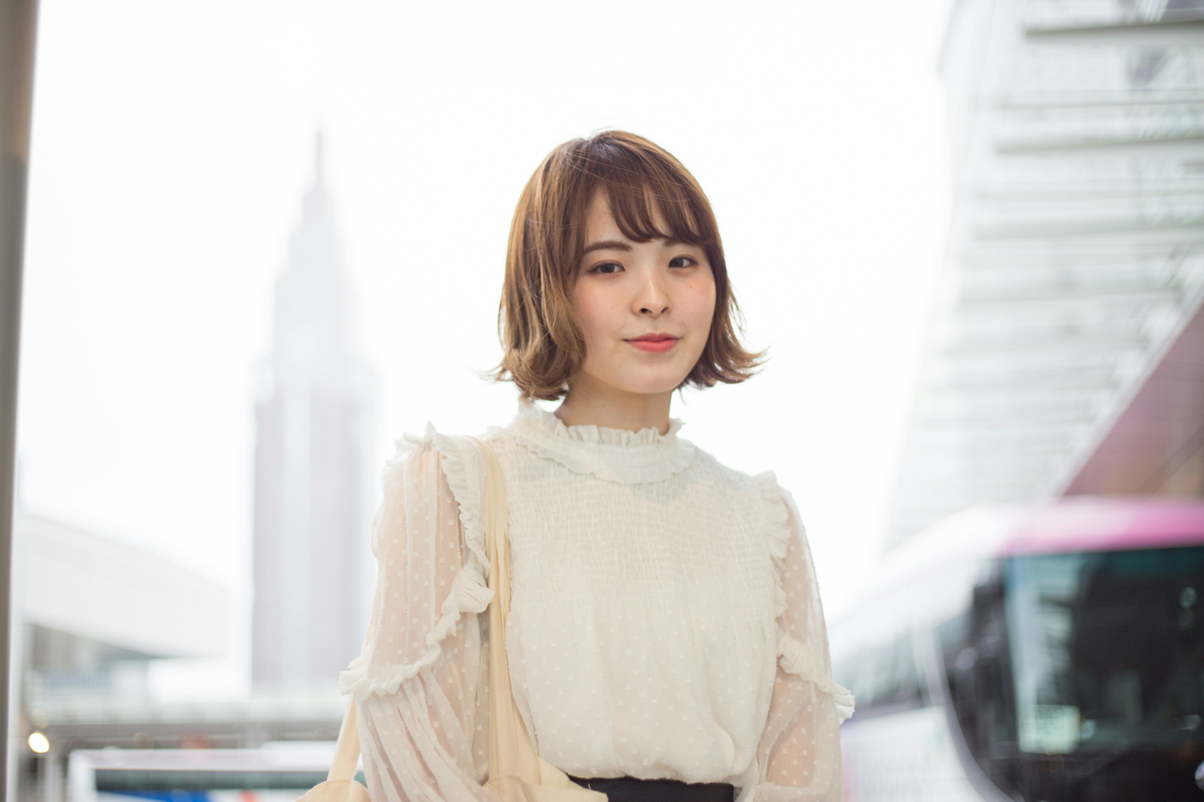 A woman in an elegant white blouse smiling against an urban background