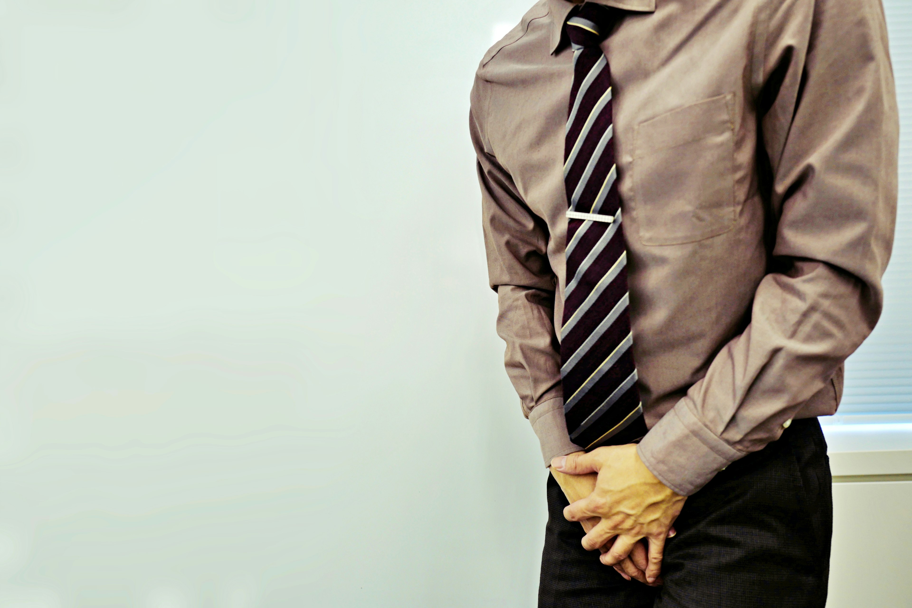 A man in business attire standing with a shy expression