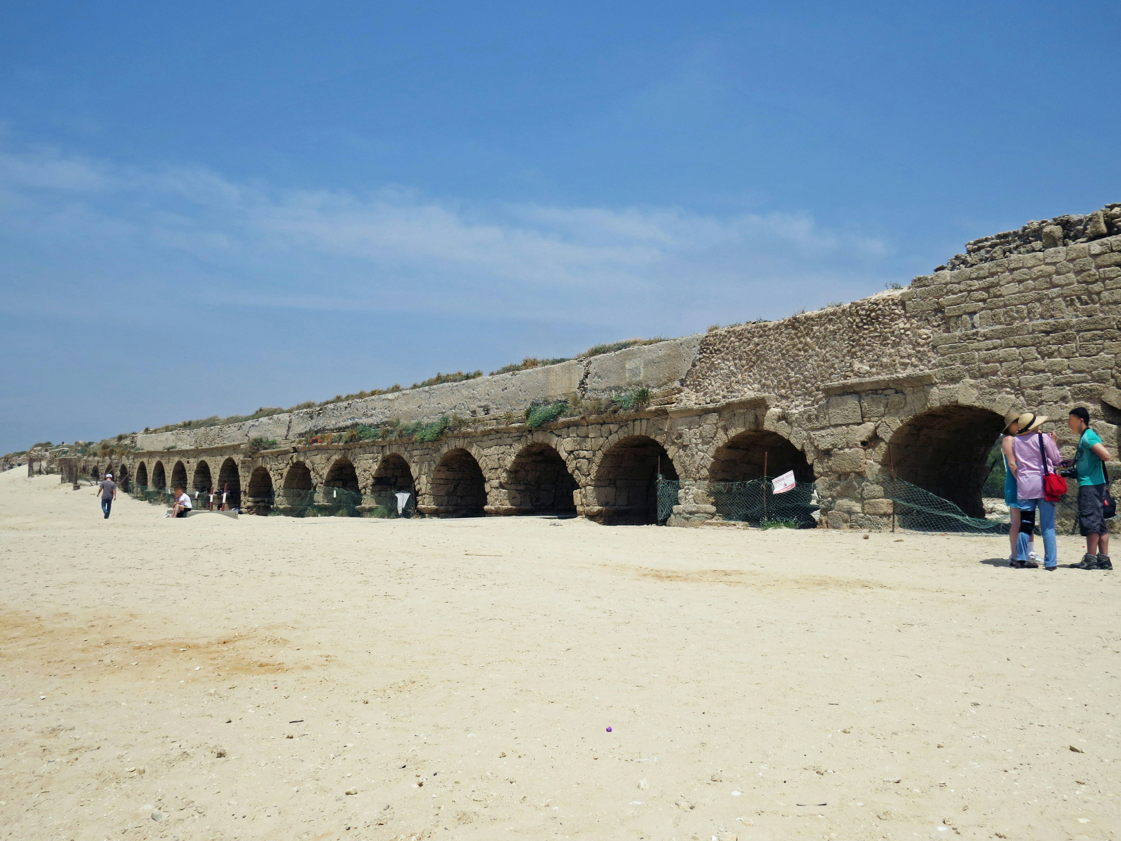 Aqueduc en pierre ancienne près de la plage avec des personnes