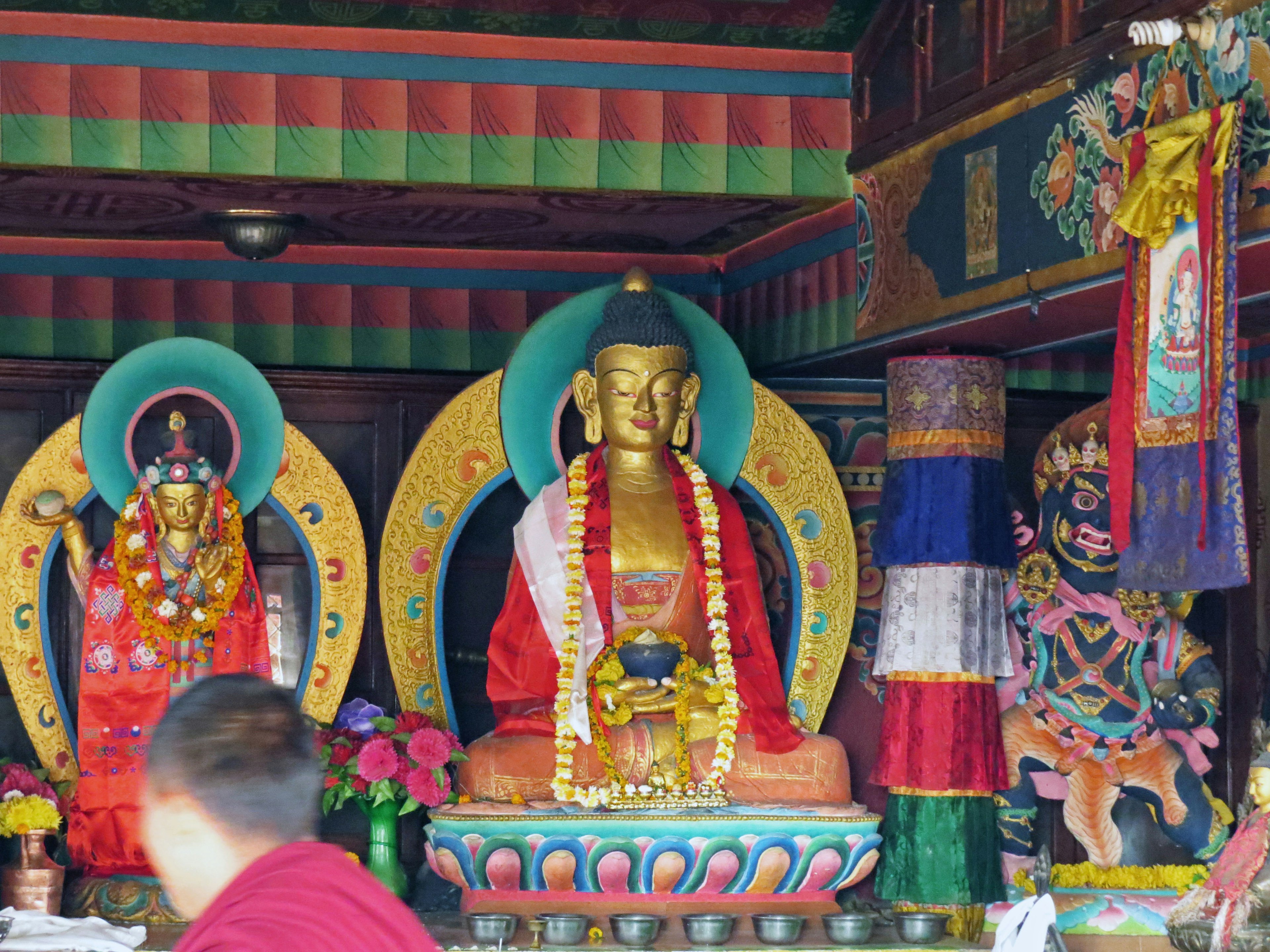 Interior of a temple featuring colorful statues and floral decorations