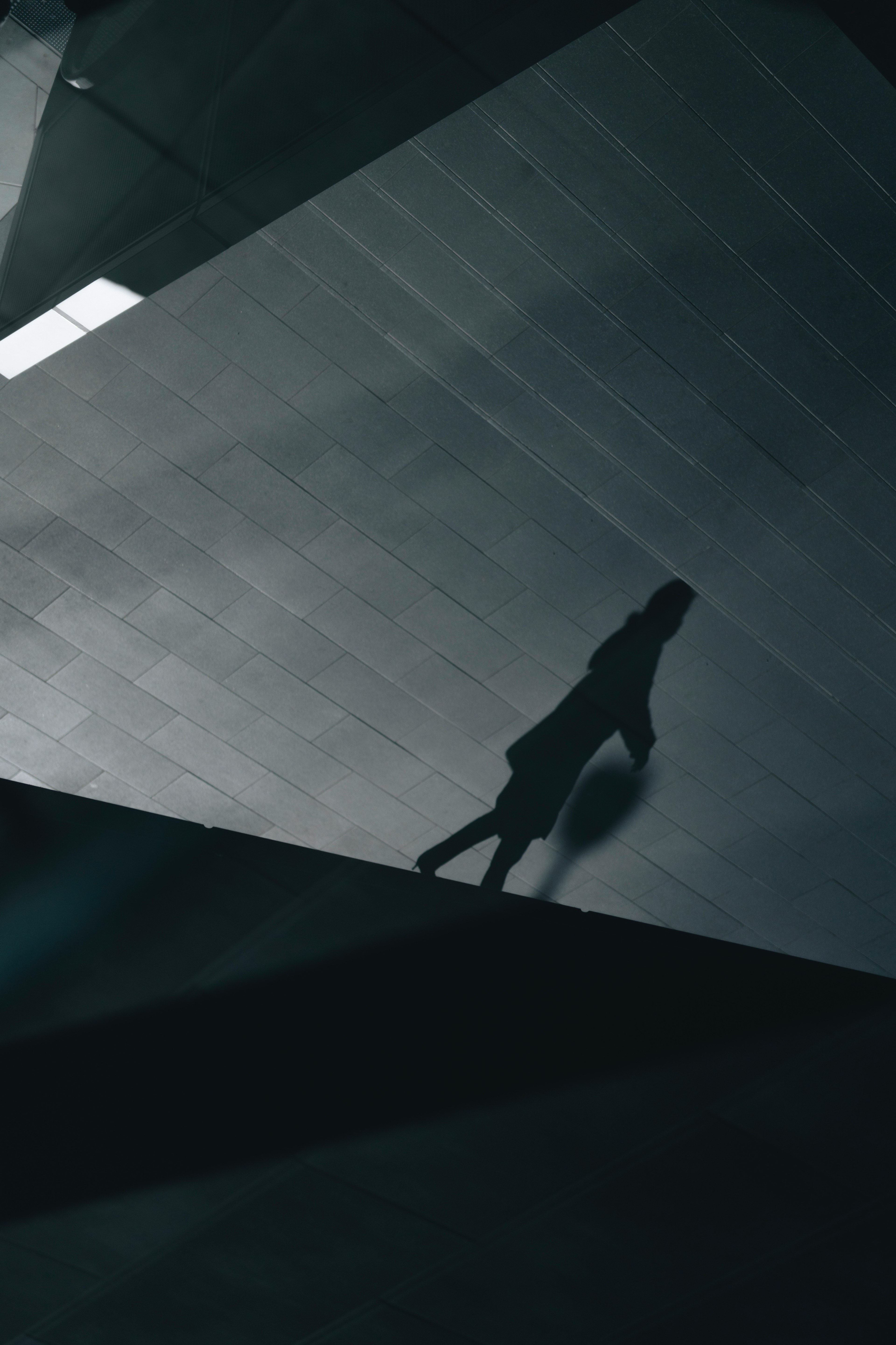 A silhouette of a person walking on geometric shapes in a dark setting