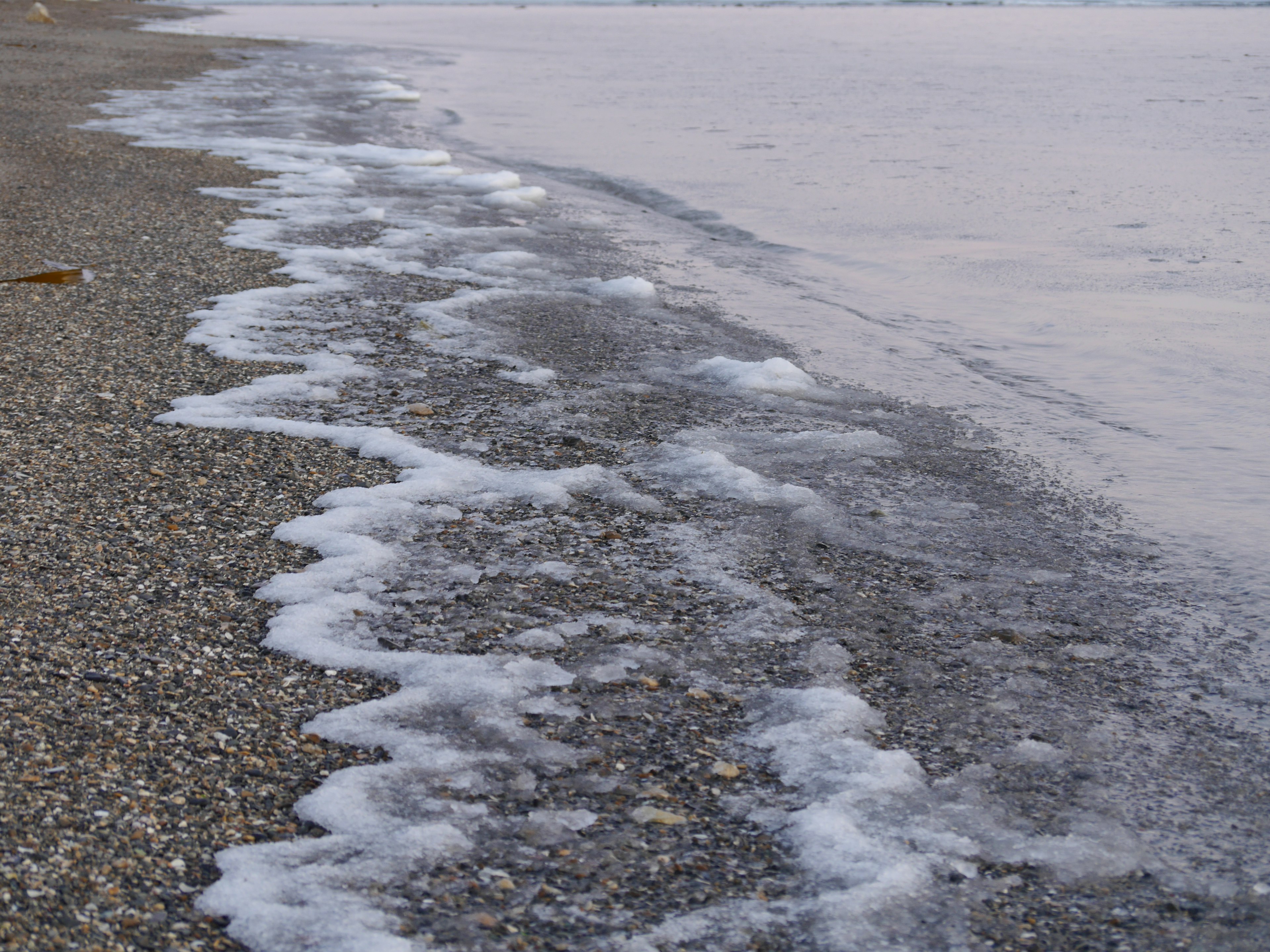 คลื่นซัดเข้าหาชายหาดหินกรวดที่ชายฝั่ง