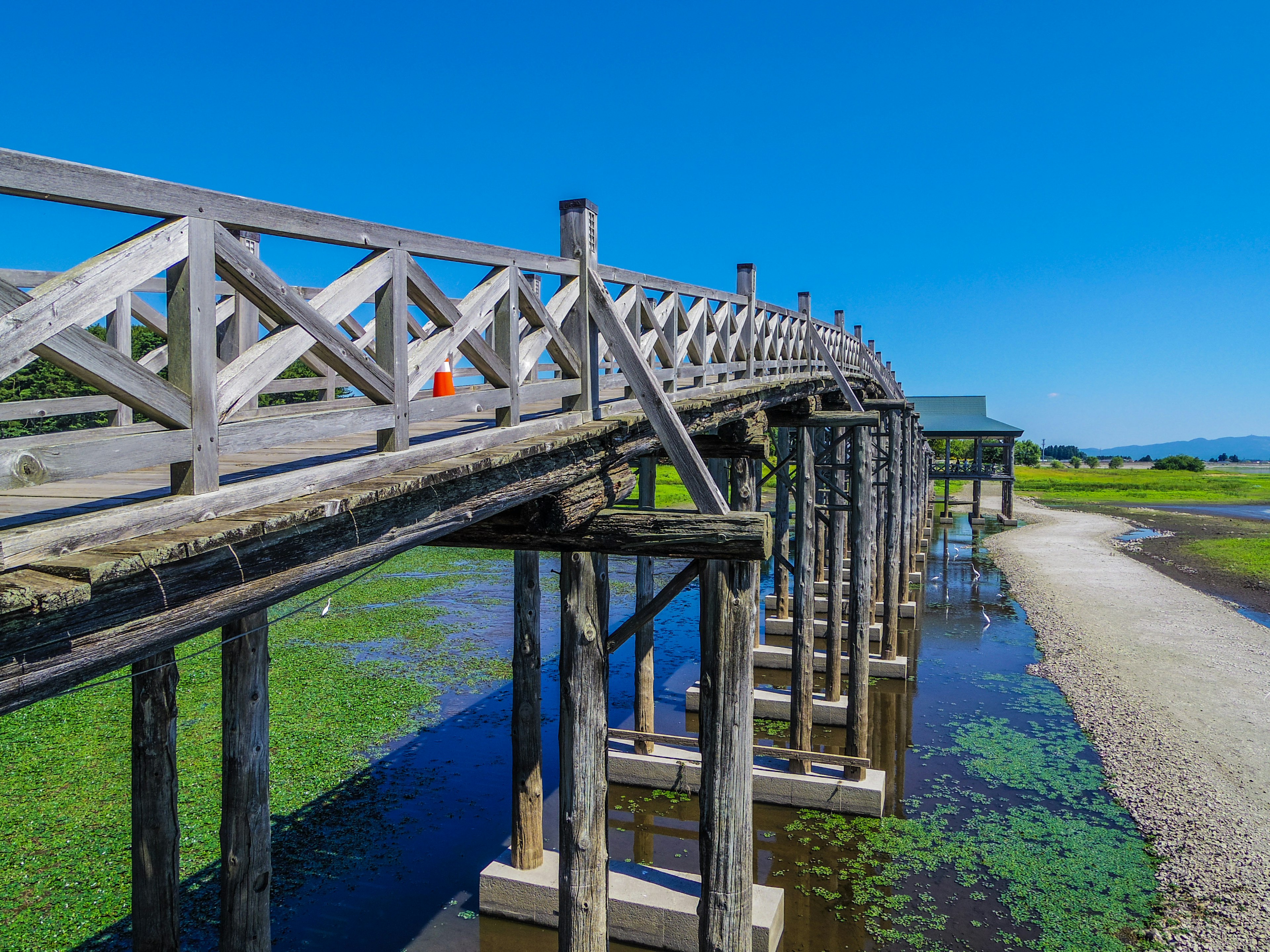 Jembatan kayu di atas air di bawah langit biru cerah