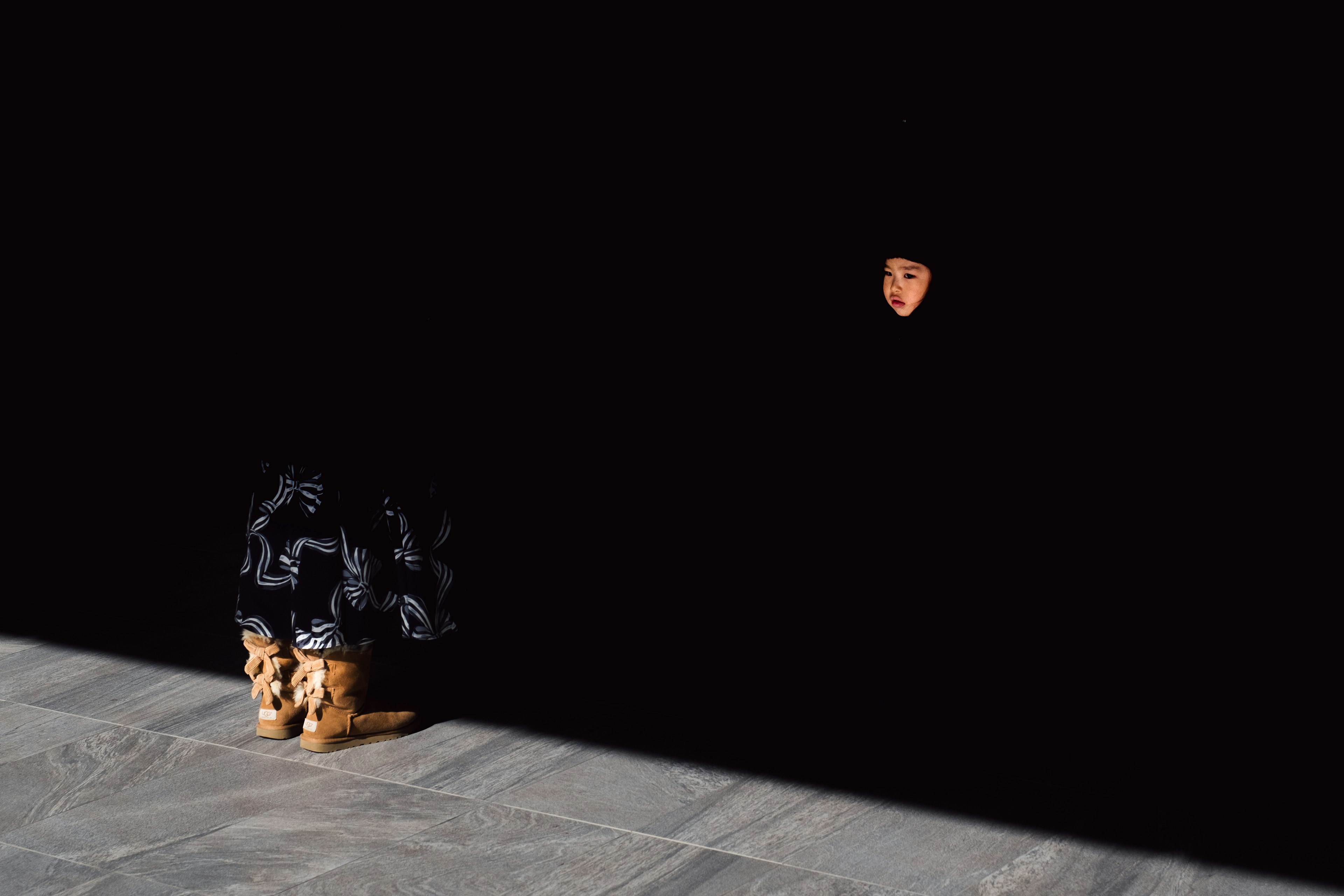 A woman sitting against a dark background with only her face partially visible