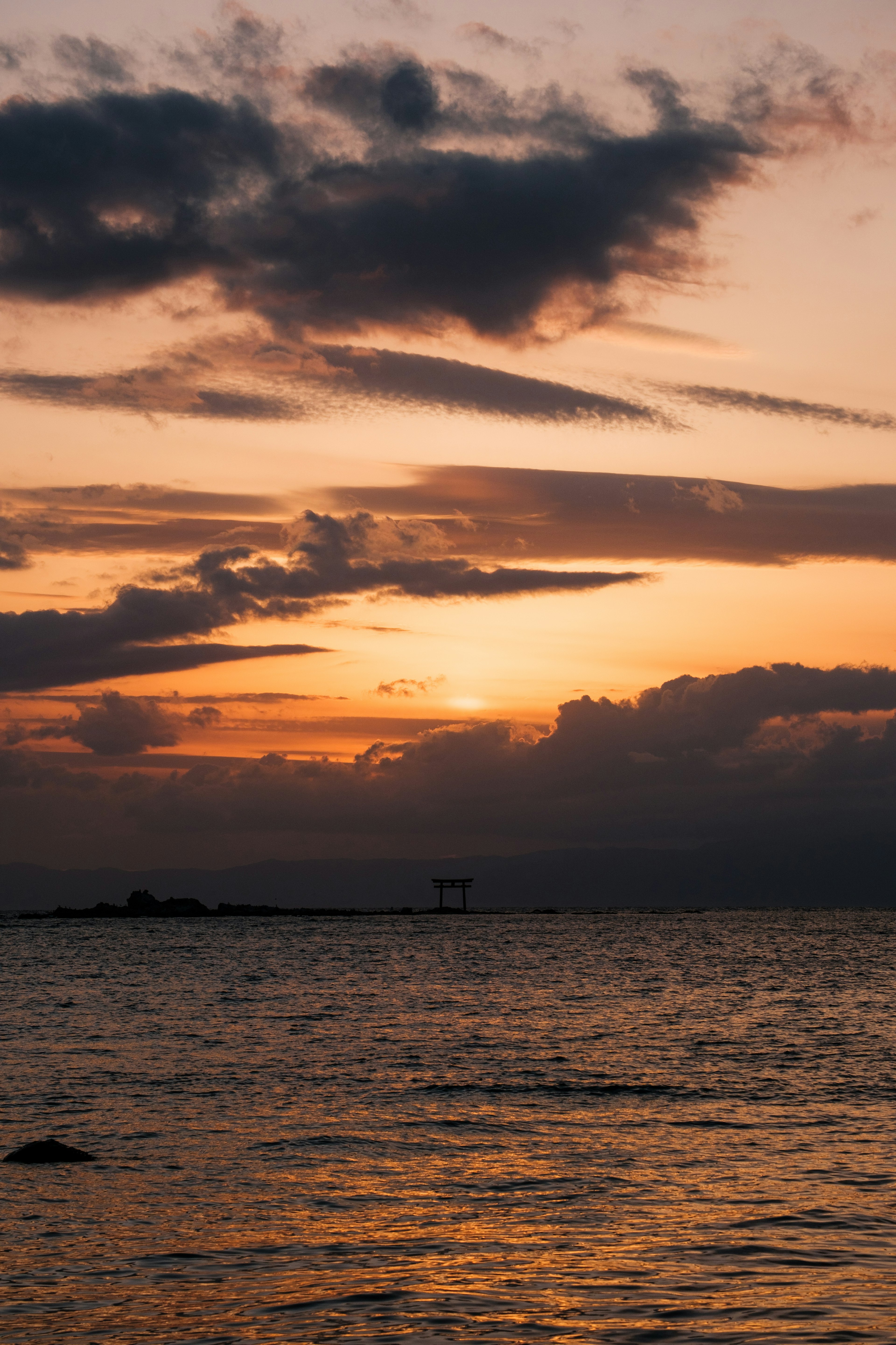 Paesaggio marino al tramonto con tonalità arancioni e blu nel cielo