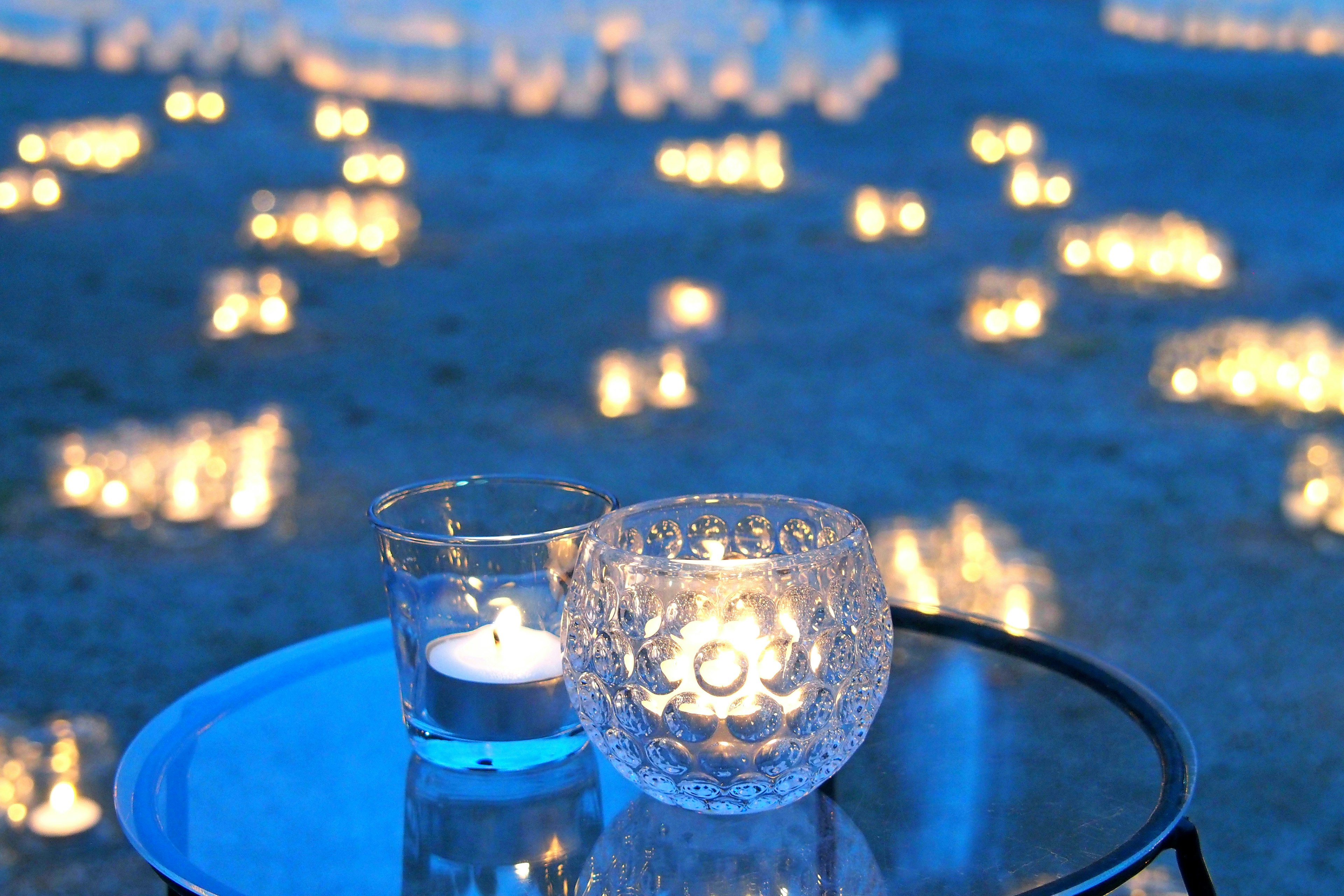 Ein Tisch mit leuchtenden Kerzen und einem Glasbehälter im blauen Licht