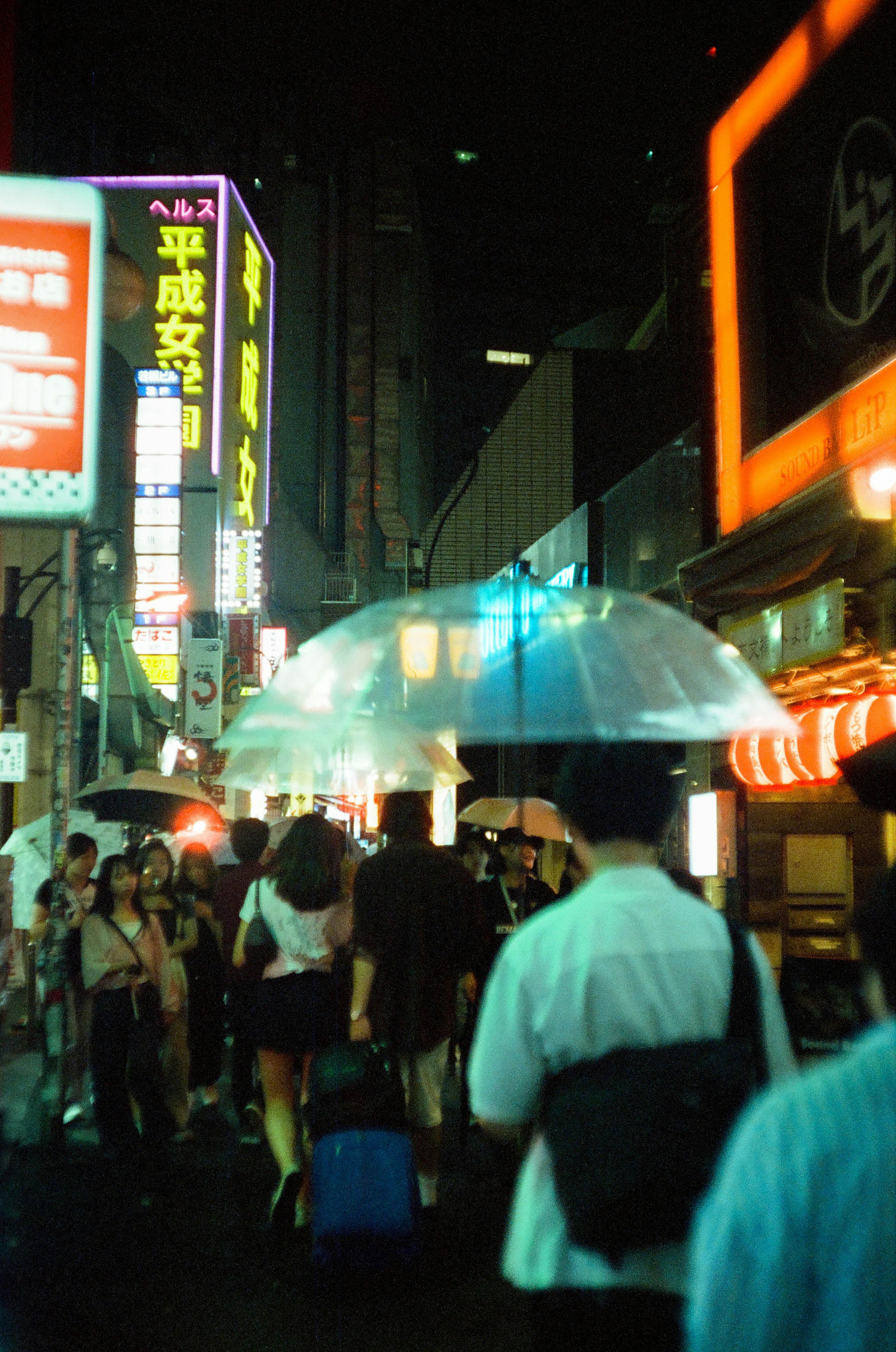 People walking in a Tokyo street at night with colorful neon signs