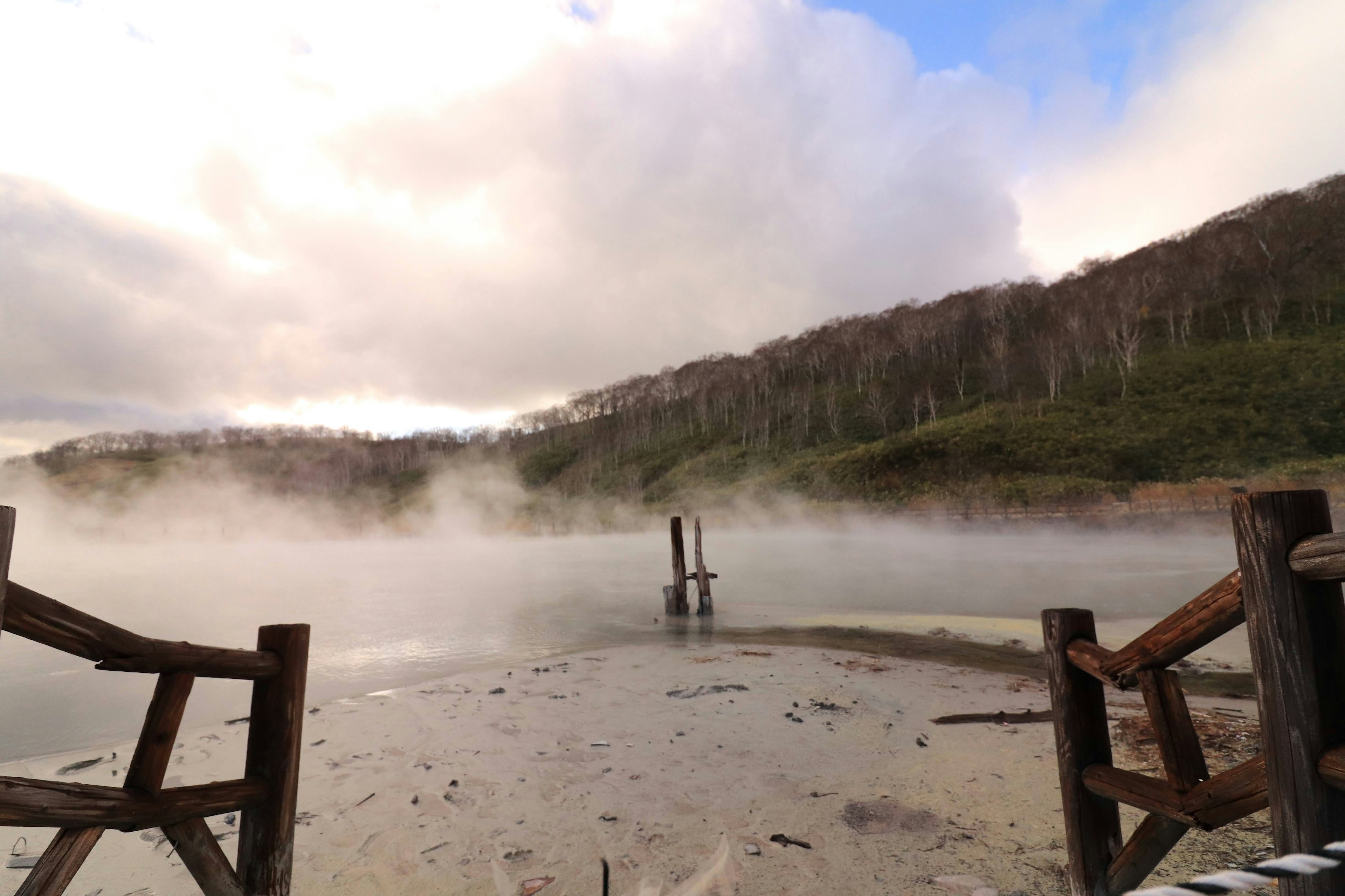 Vista nebbiosa di un lago con colline verdi sullo sfondo