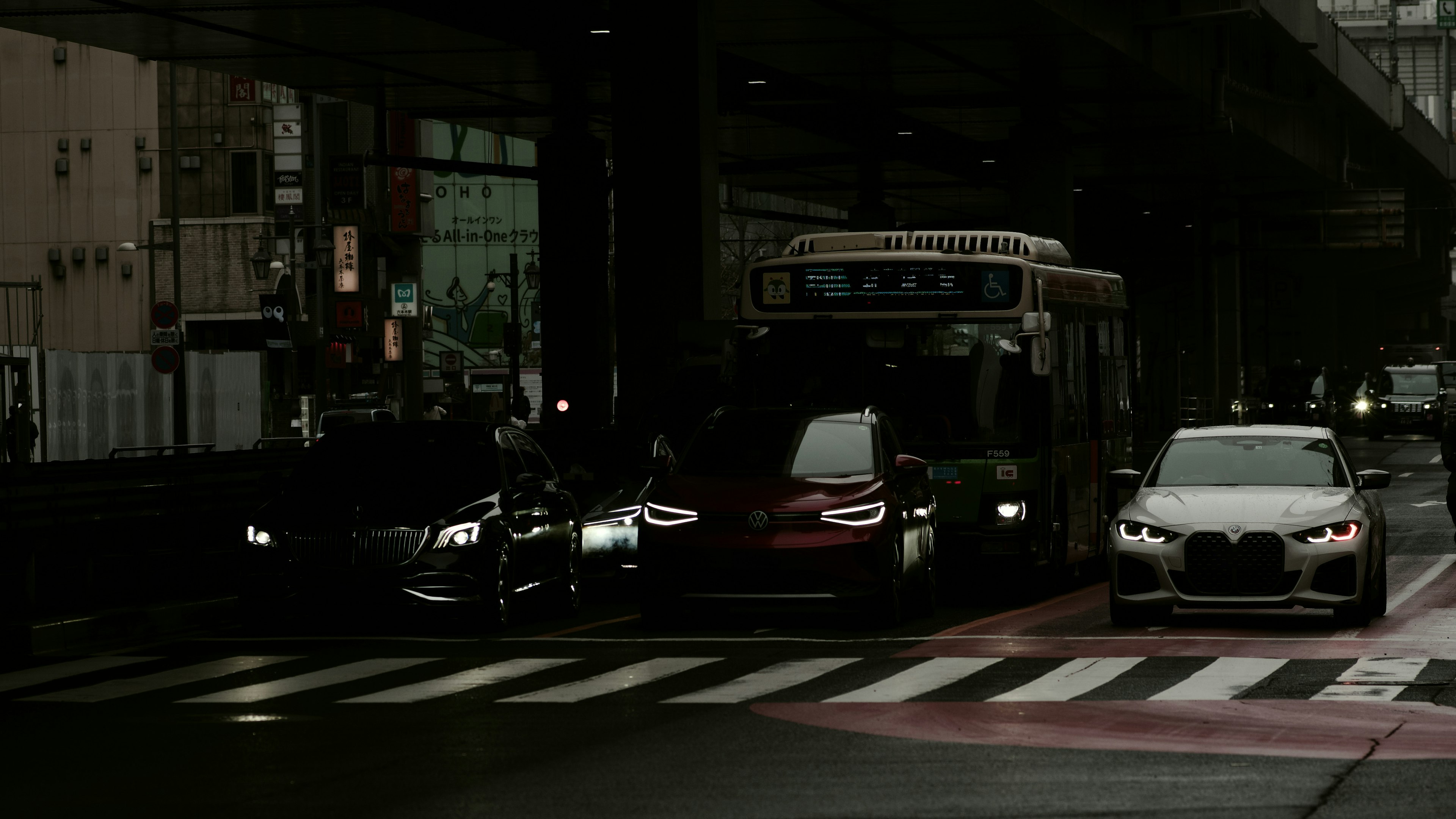 暗い都市の交差点で停車中の車とバス