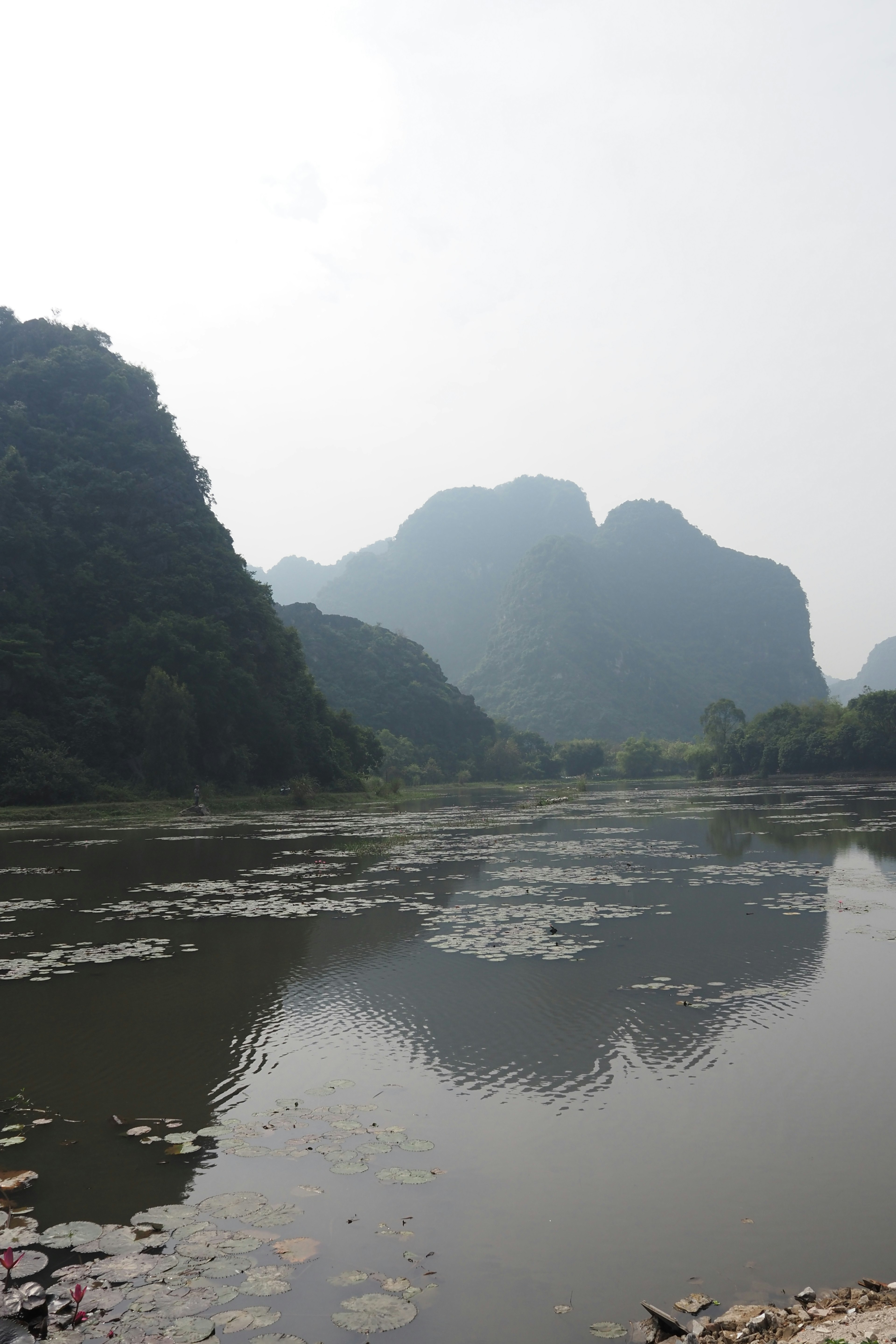 Danau tenang dengan pegunungan berkabut di latar belakang