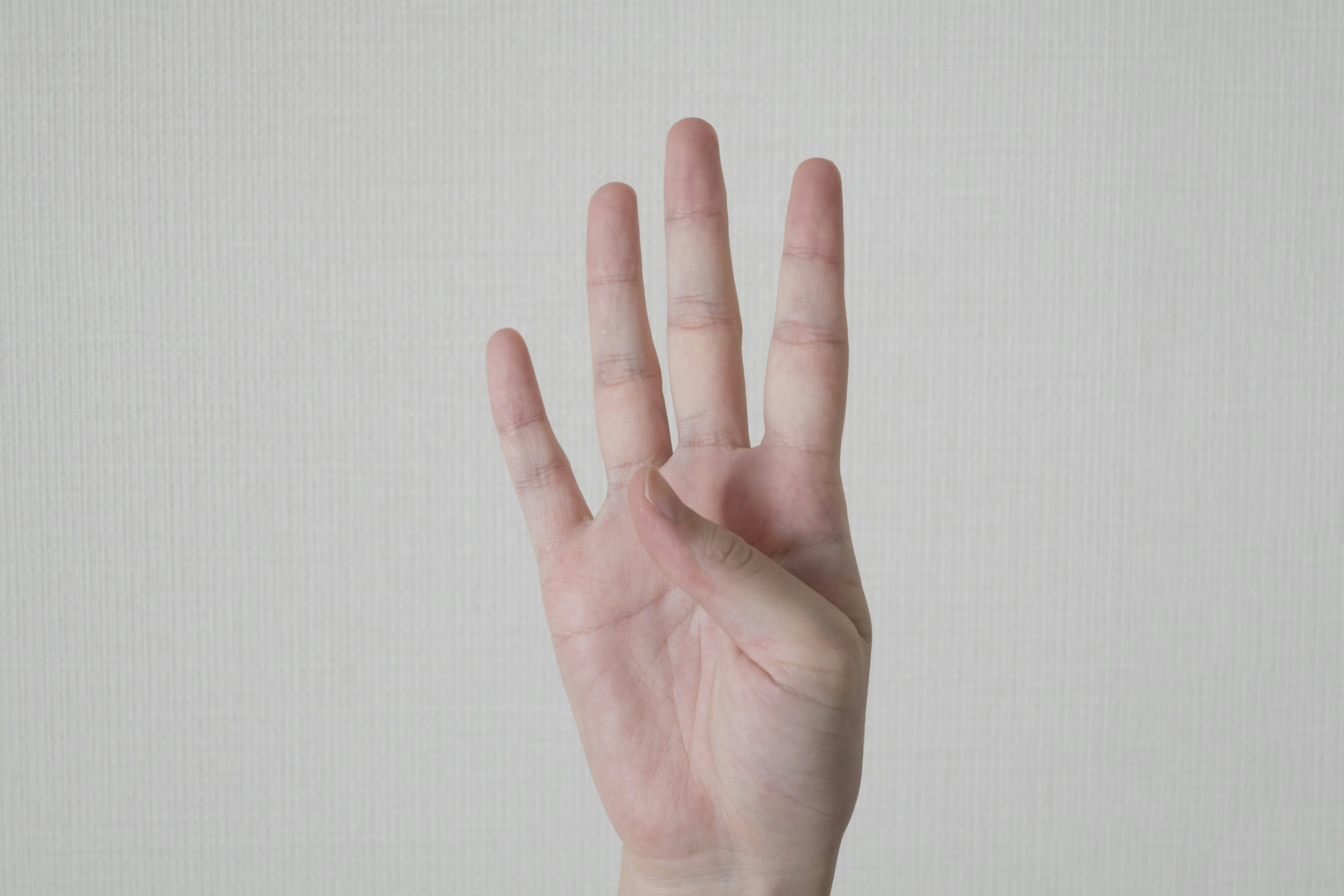 Hand showing four fingers against a white background