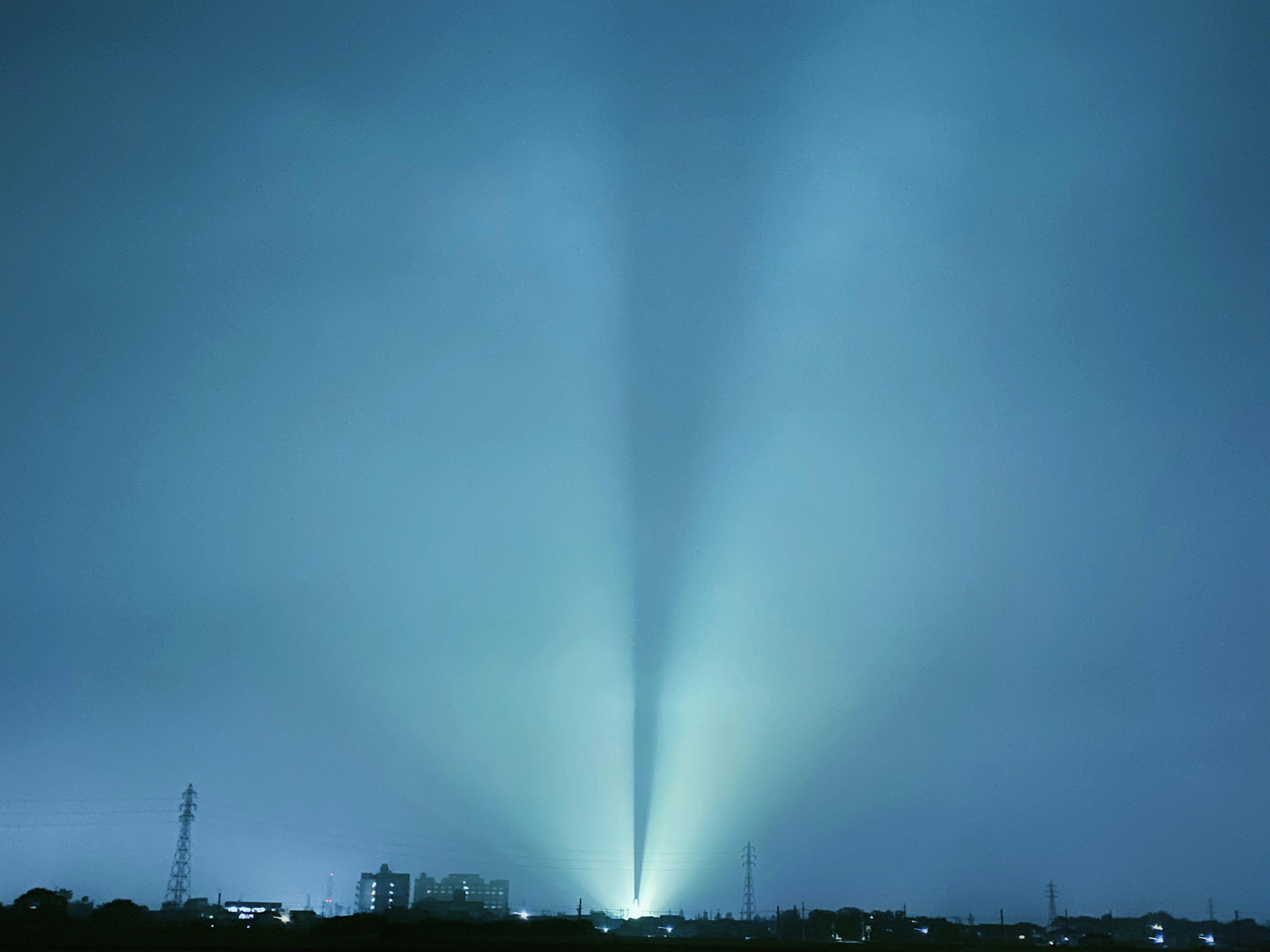 Vue nocturne avec des faisceaux de lumière bleue s'étendant dans le ciel