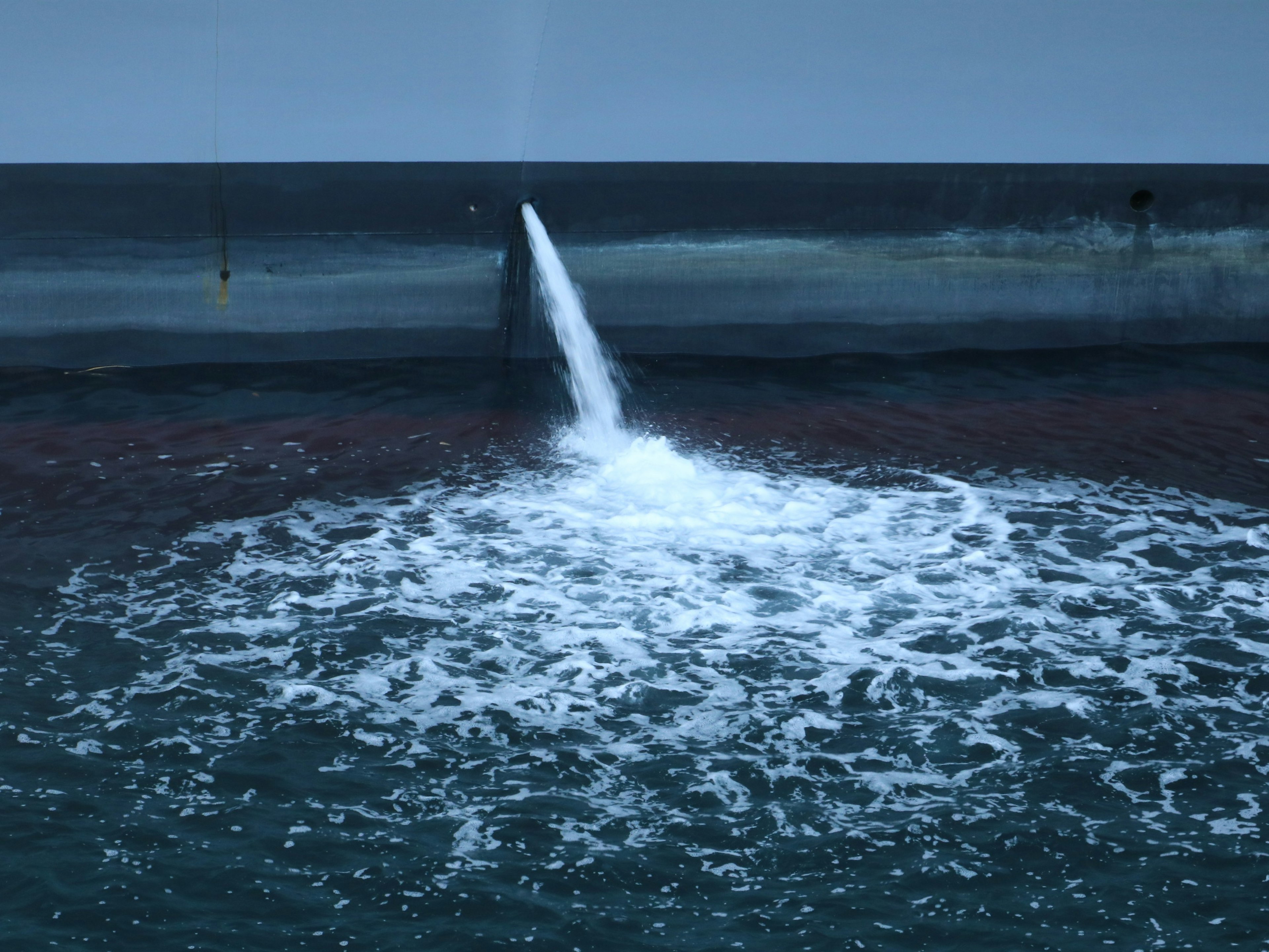 Chorro de agua en la superficie del océano con agua oscura