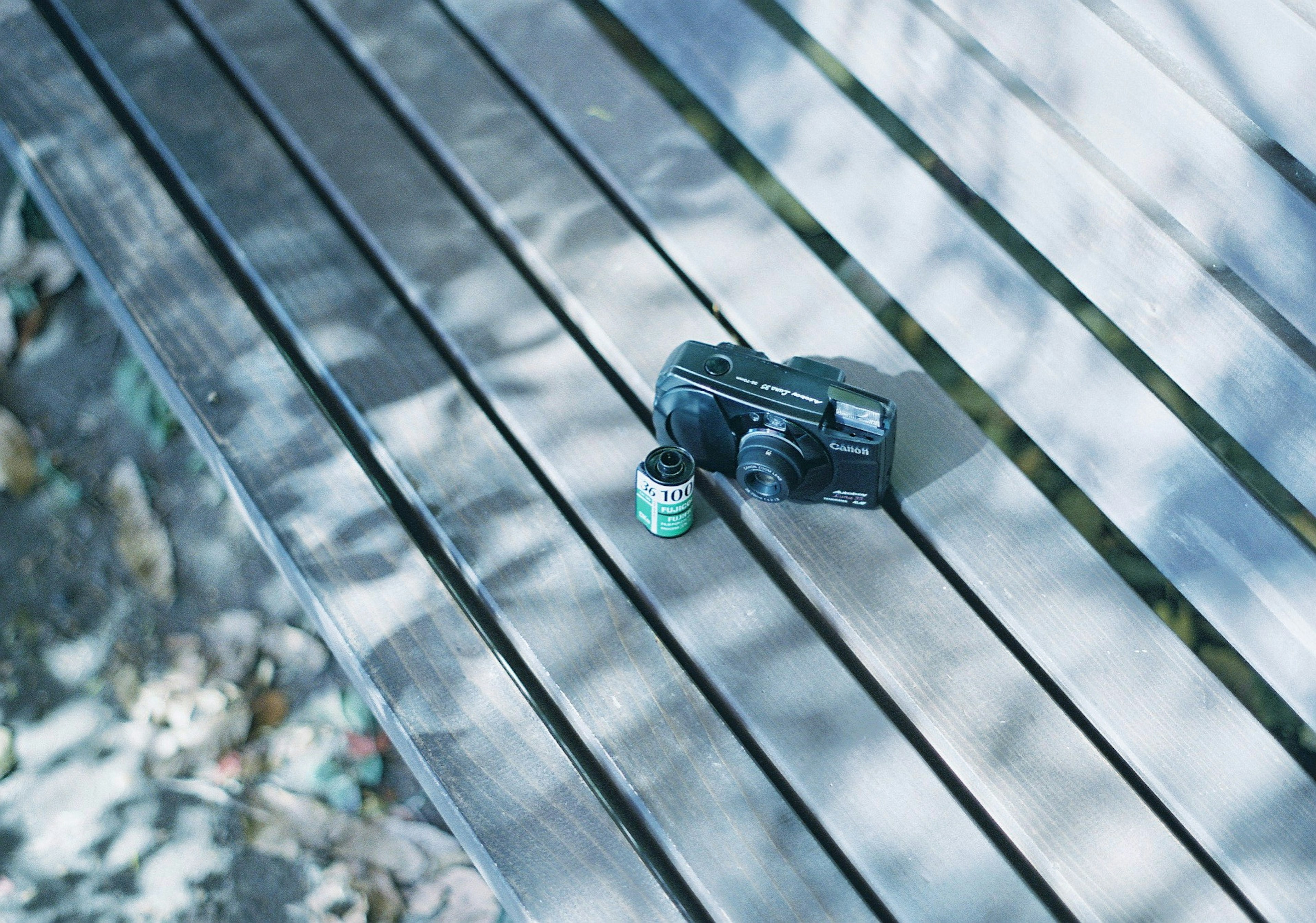 Camera and film canister on a wooden bench