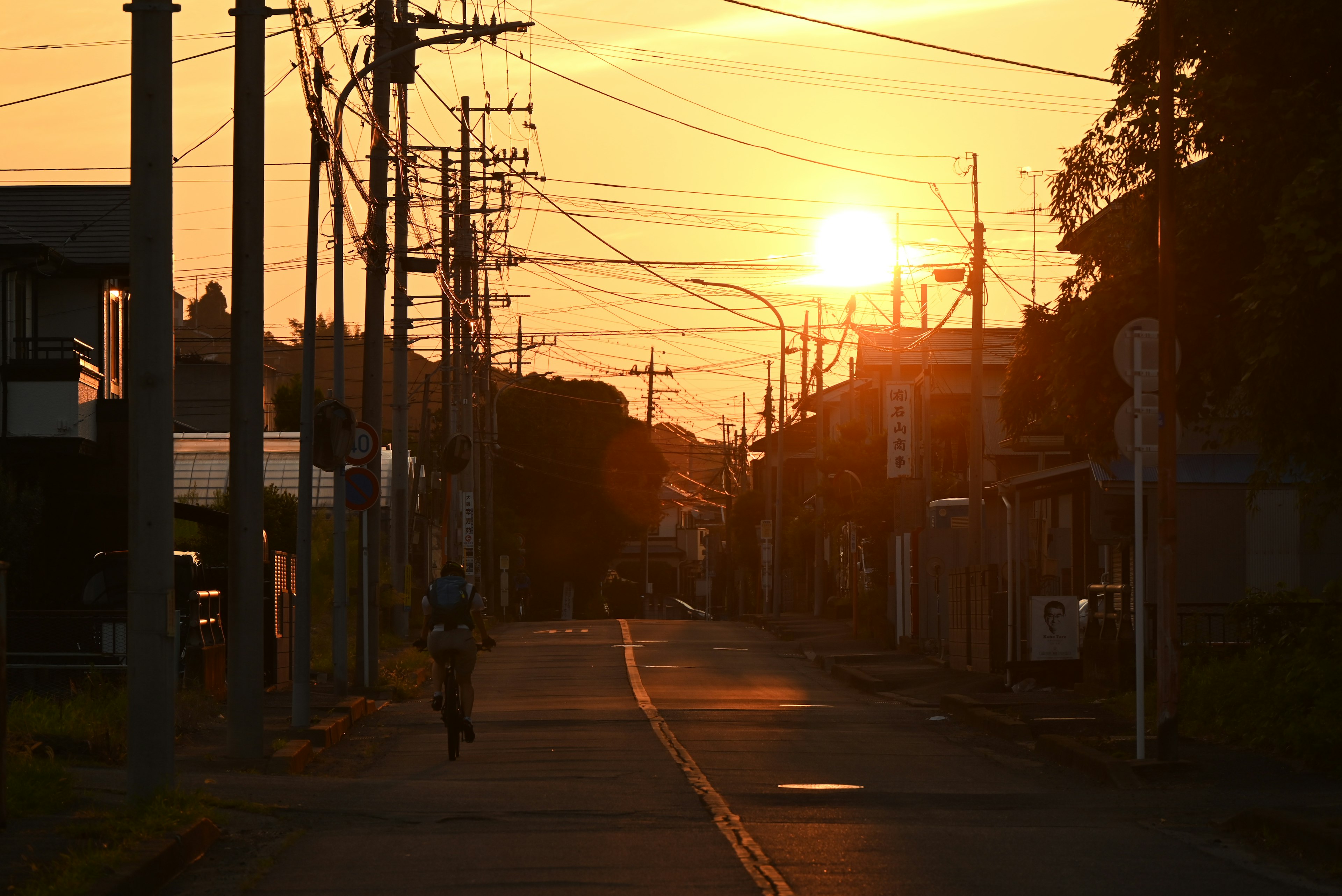 Un cycliste sur une rue vide avec un coucher de soleil en arrière-plan