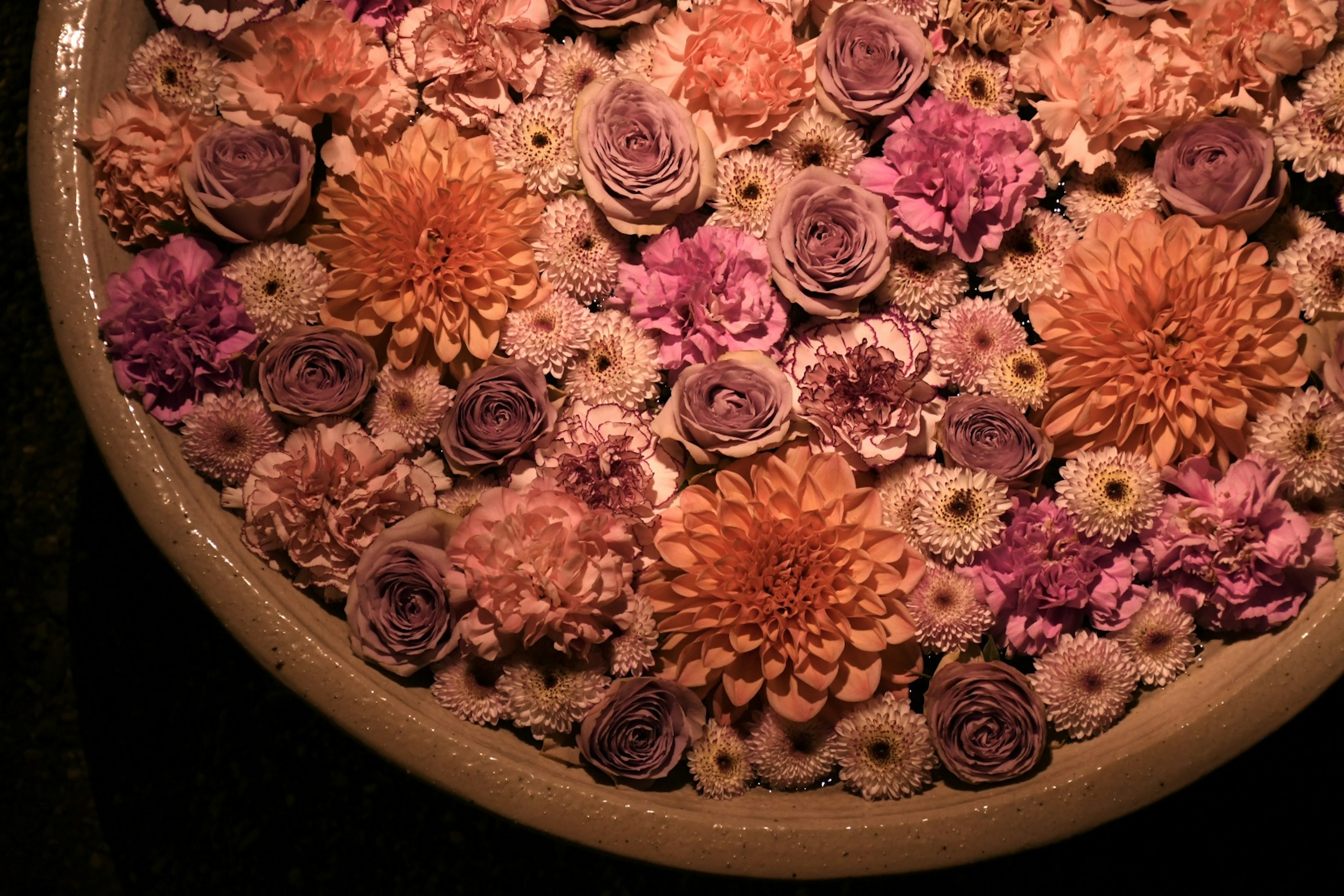 Un gran tazón lleno de flores rosas y naranjas dispuestas cuidadosamente