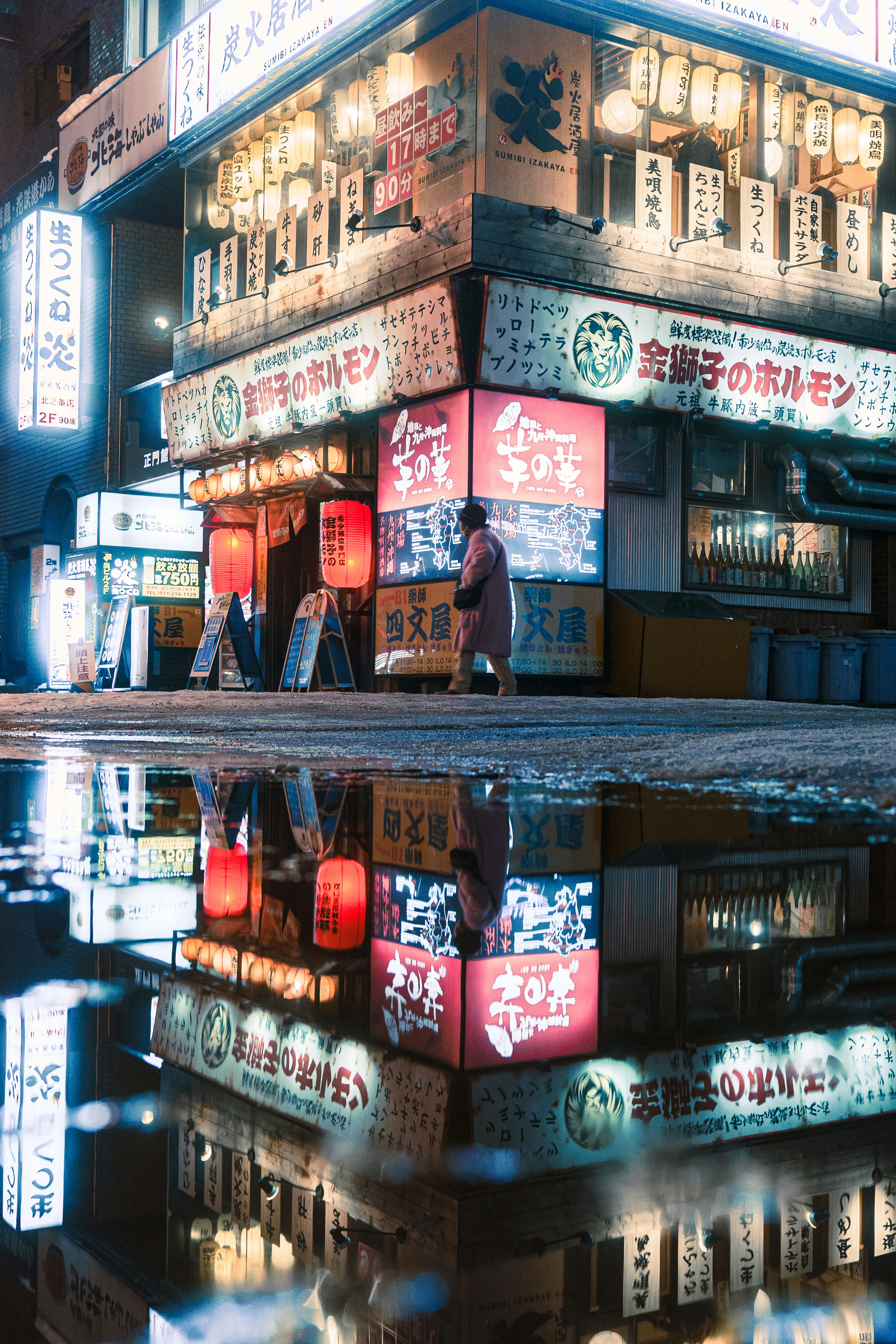 Neon signs reflecting in a puddle on a city street at night