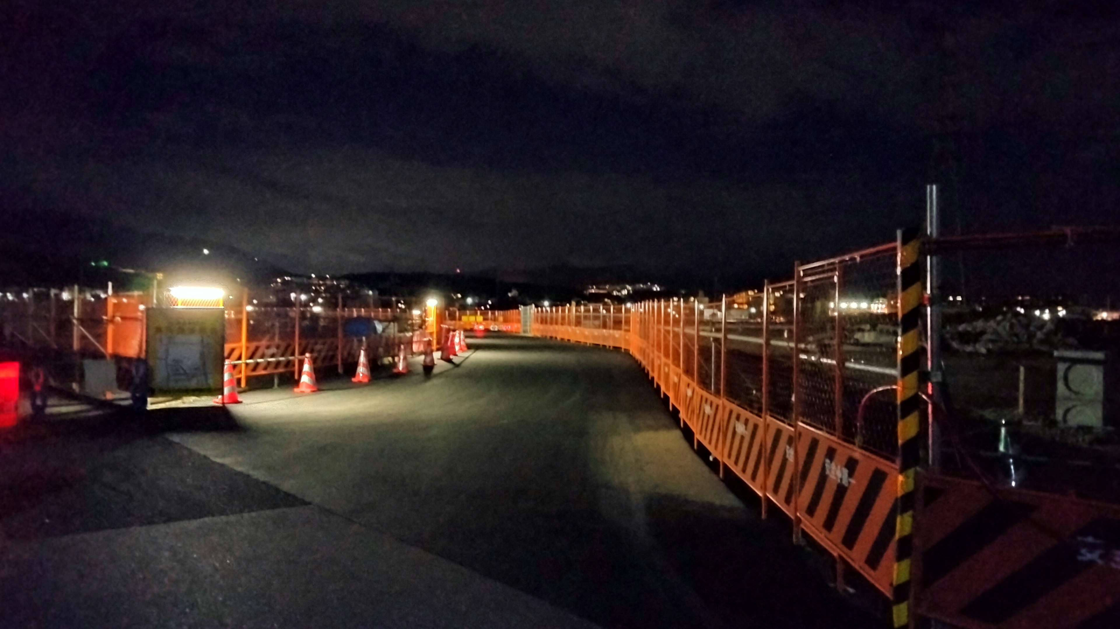 Sitio de construcción nocturno con barricadas naranjas iluminadas