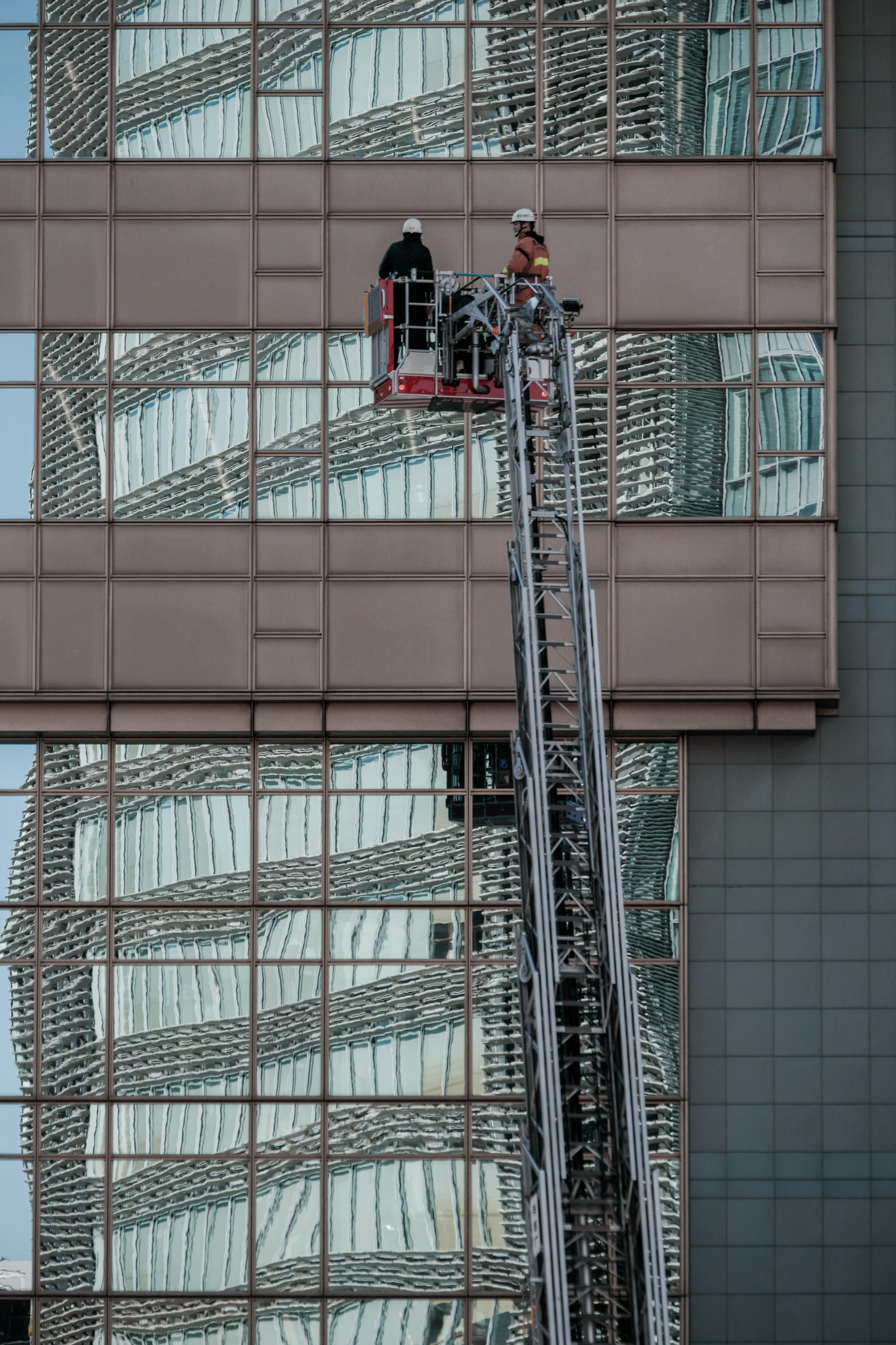 고층 건물에서 작업자가 리프트를 사용하여 창문을 청소하고 있다