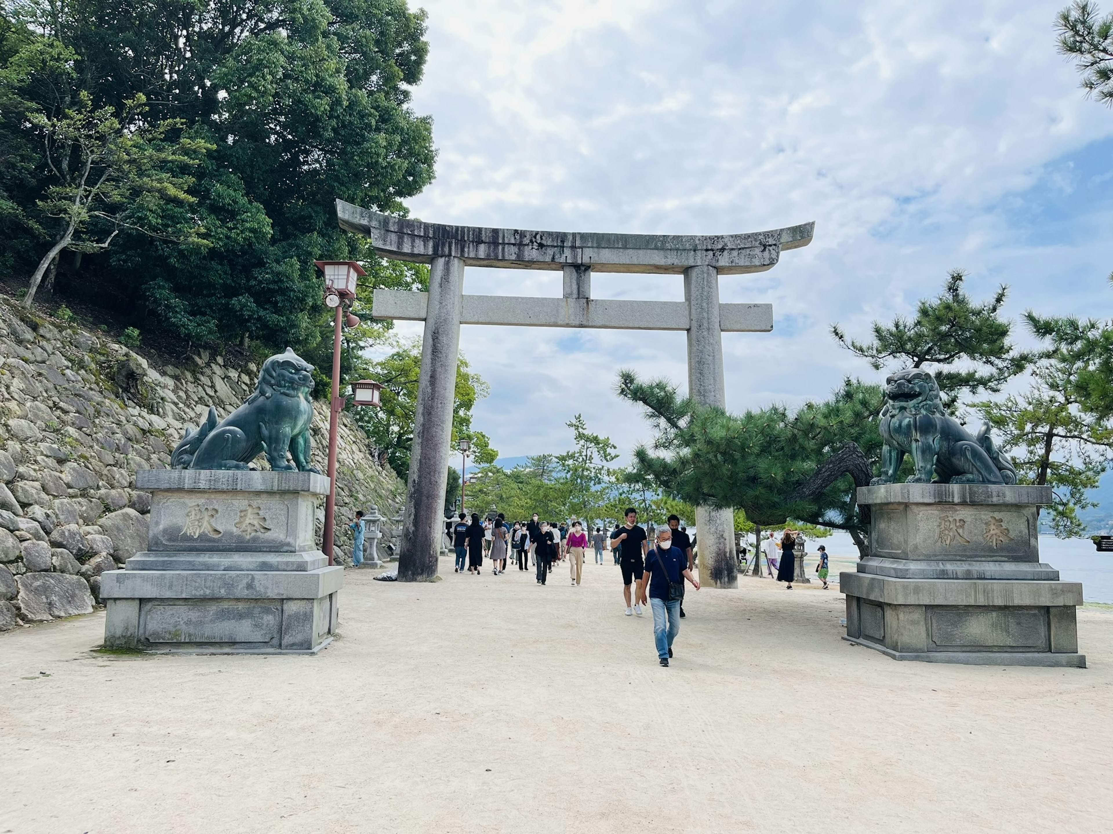 鳥居と狛犬がある神社の入り口 多くの人々が訪れている