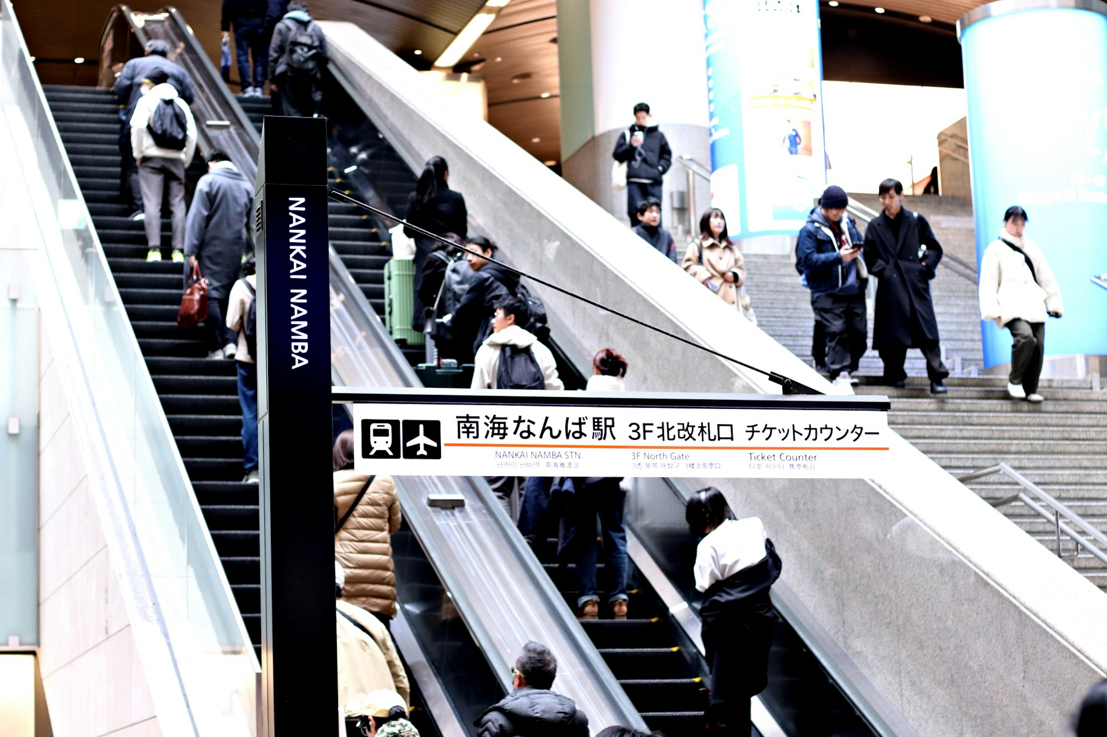 Vista interior de una estación con muchas personas usando la escalera mecánica