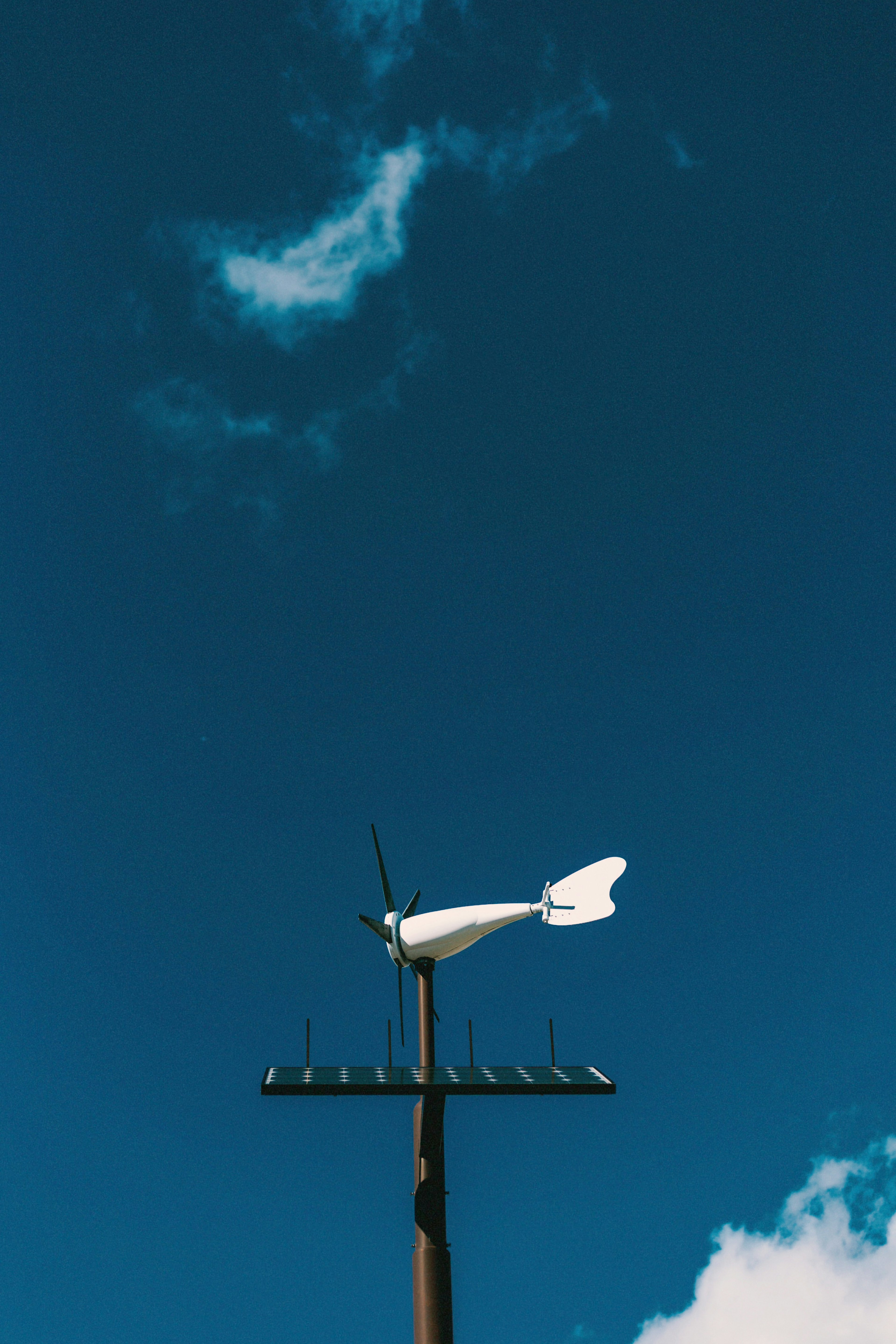 Vane à vent blanc monté sur un poteau contre un ciel bleu