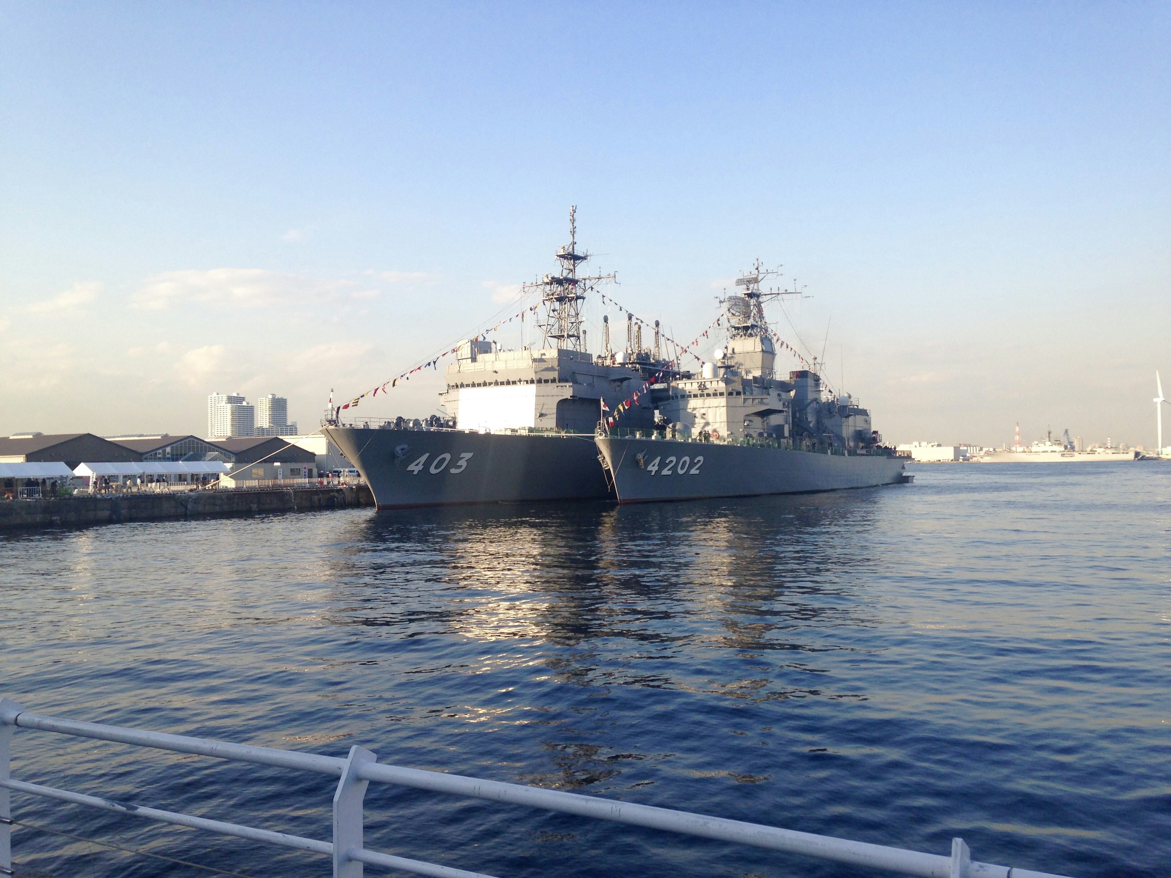 Image of military ships docked in the water with a blue sky in the background