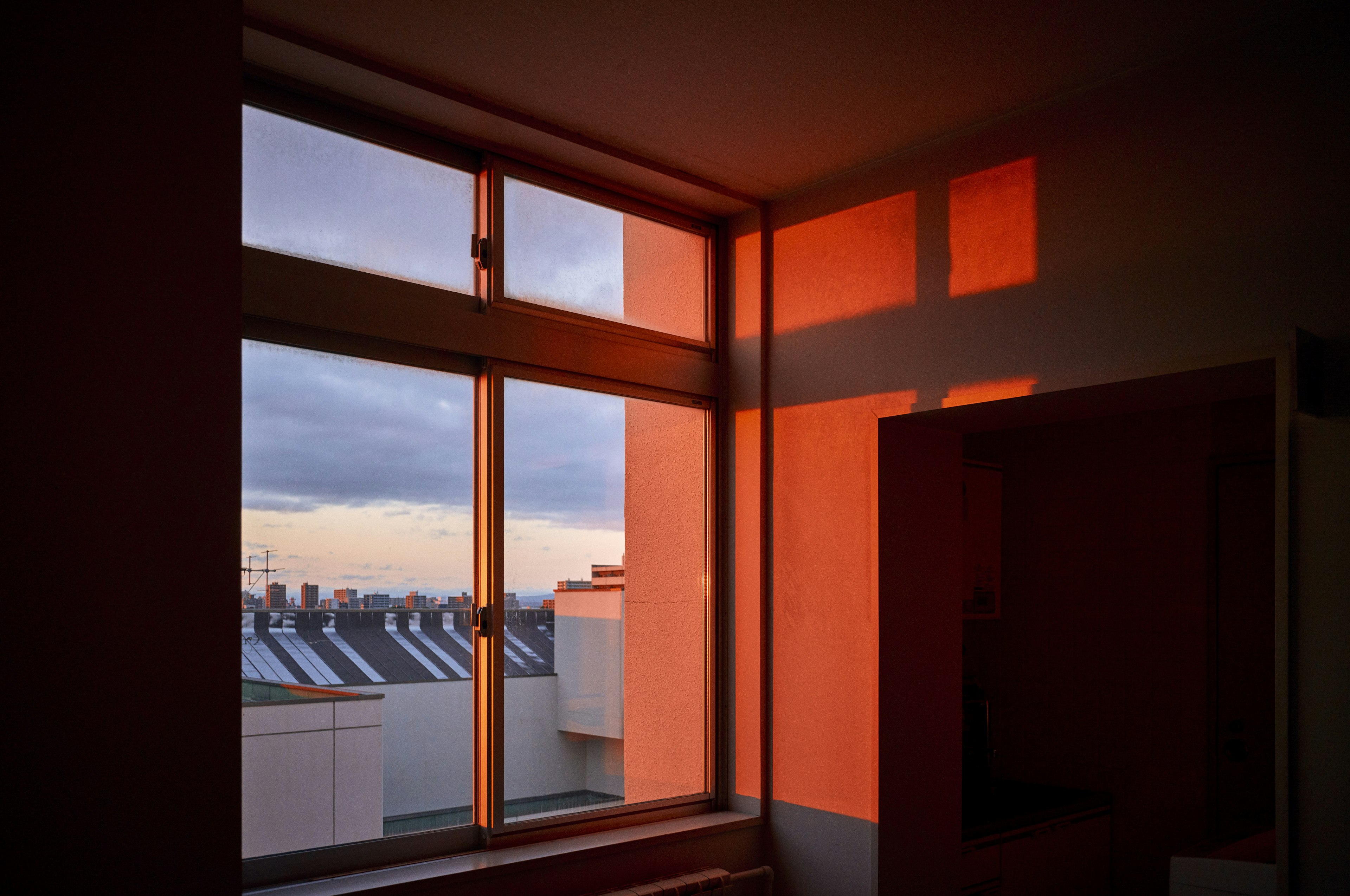 Intérieur d'une pièce avec une fenêtre montrant la lumière du coucher de soleil