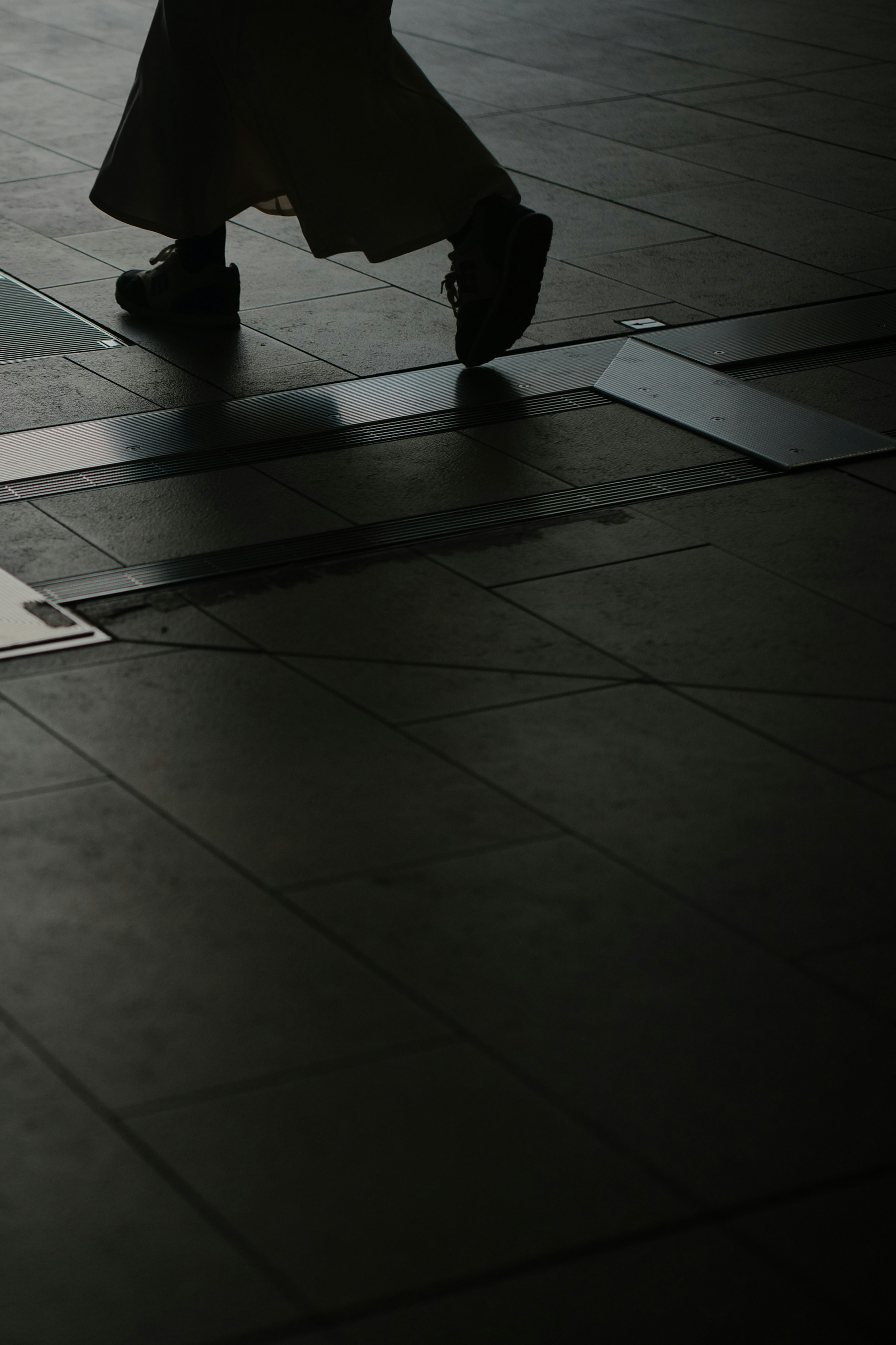 Silhouette of a person walking in a dimly lit area