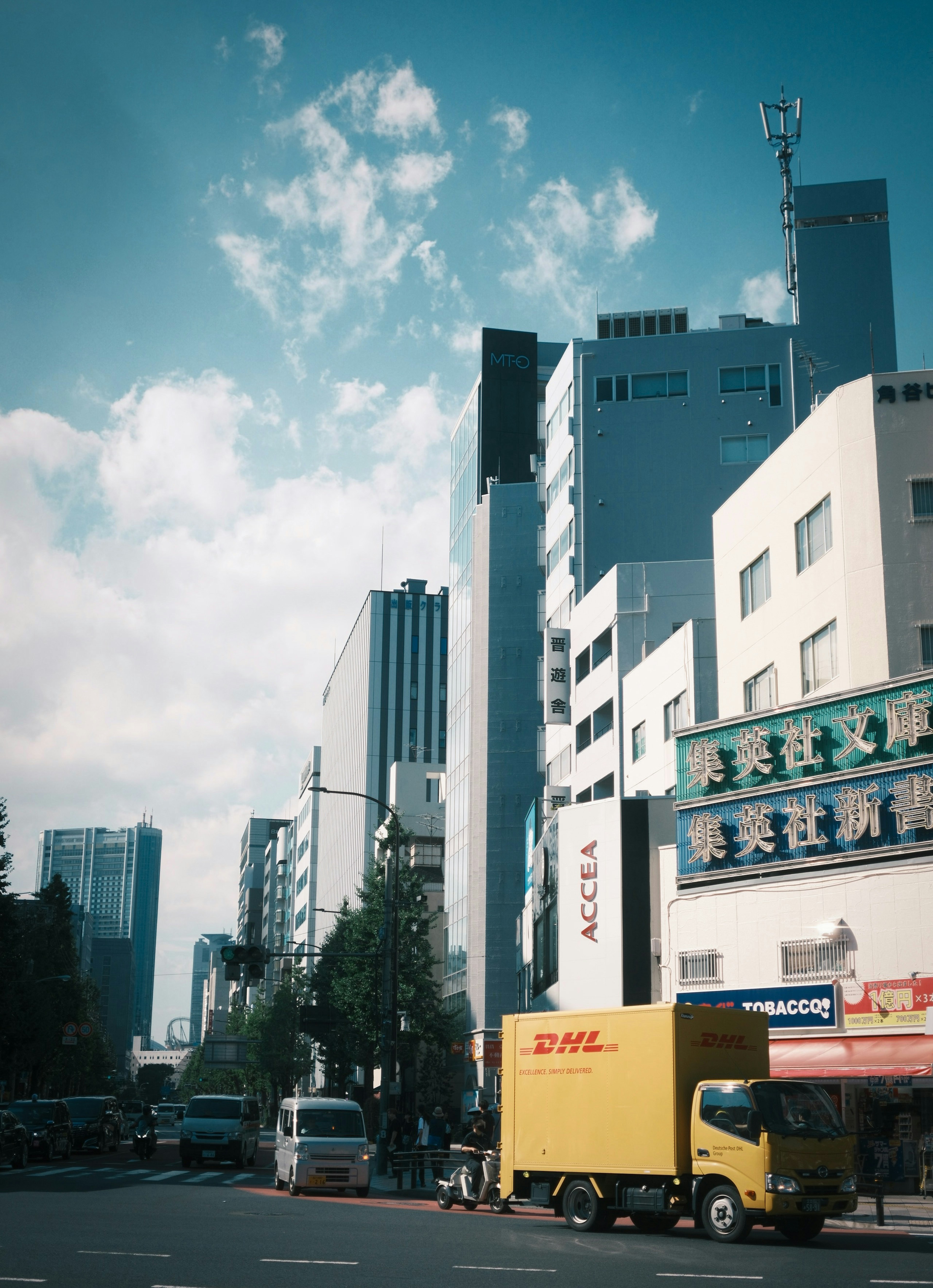 青空の下に立ち並ぶビルとトラックの風景