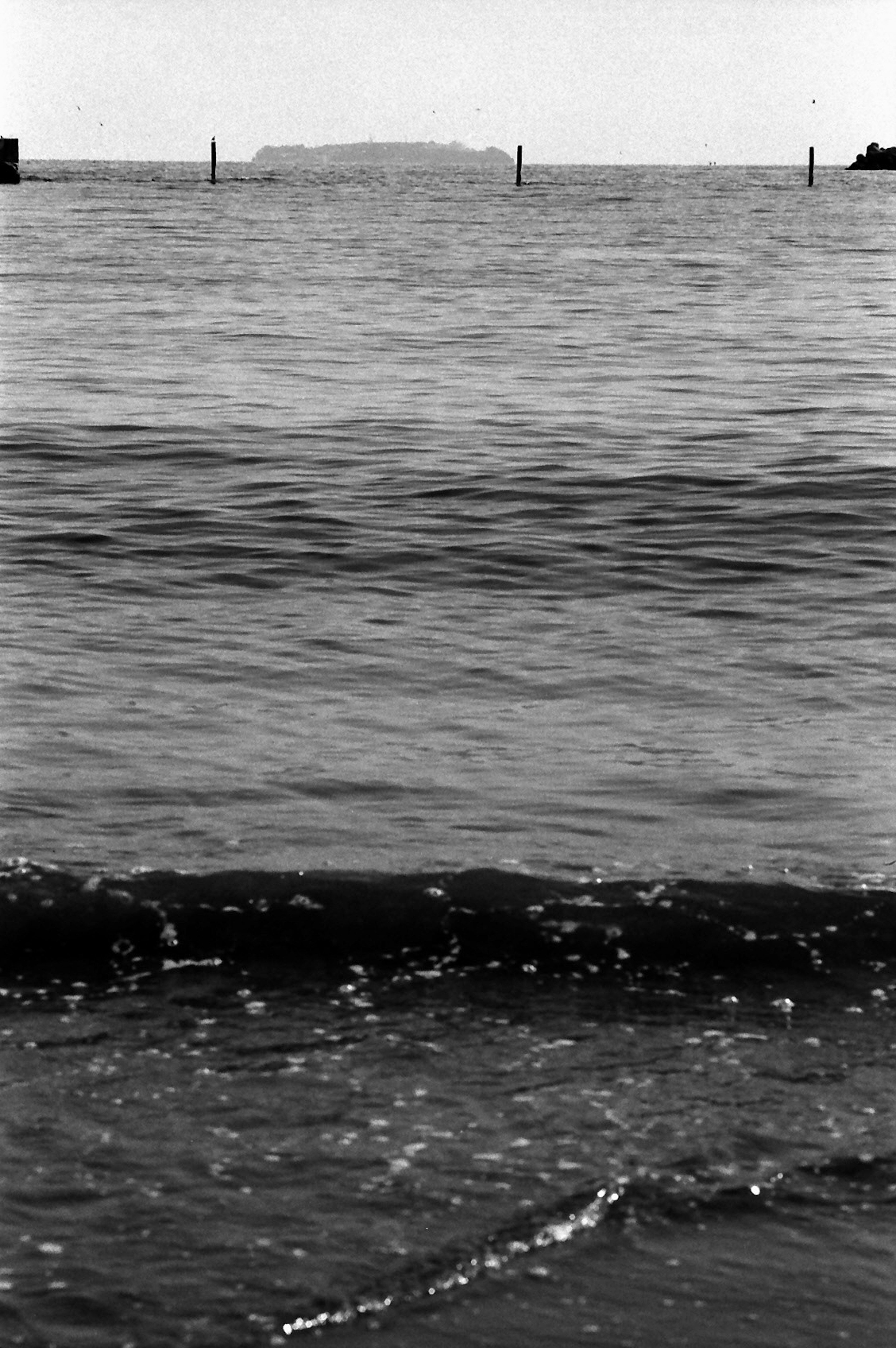 Foto in bianco e nero di onde oceaniche con un'isola in lontananza