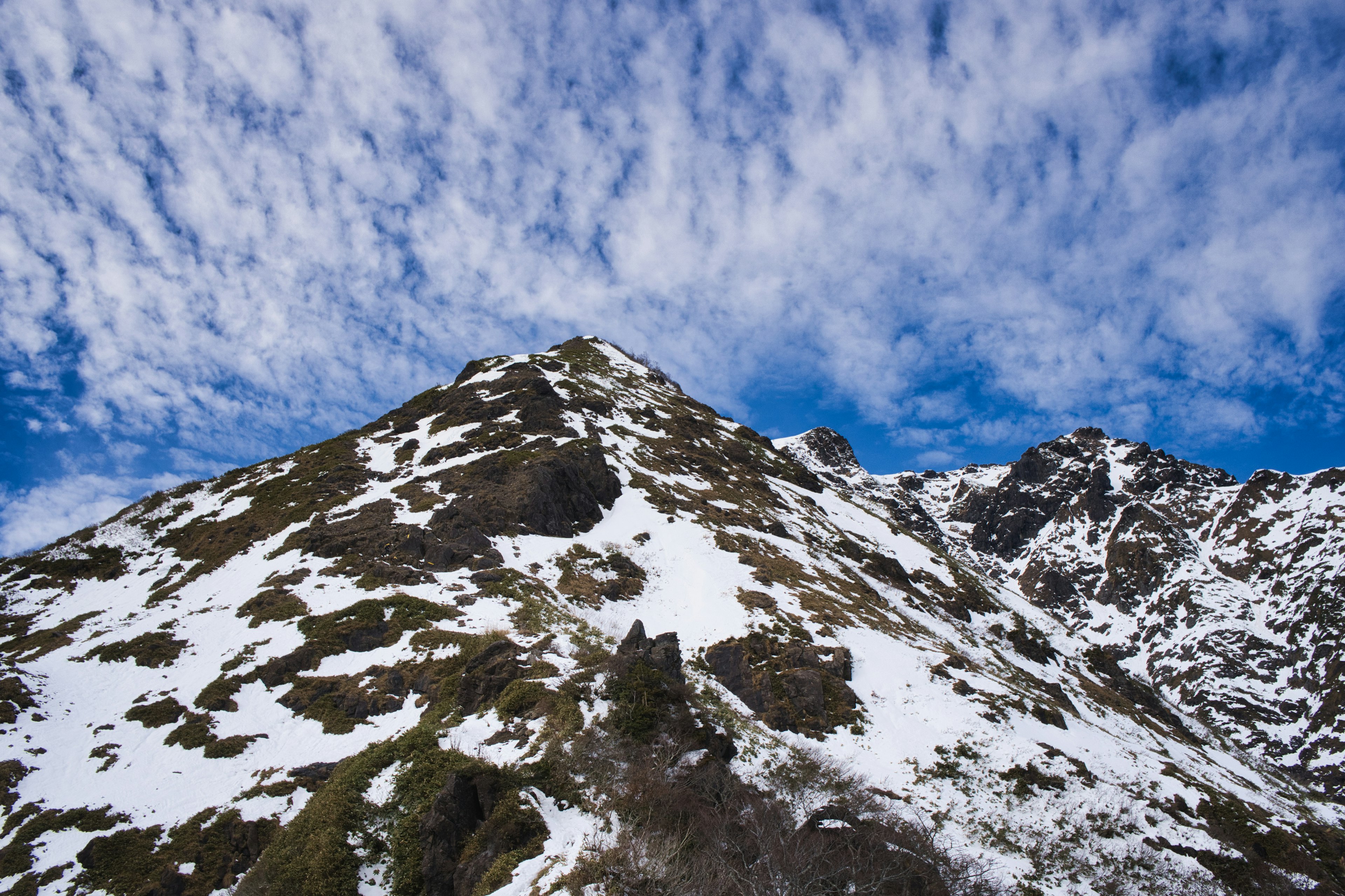 Sommet de montagne recouvert de neige avec un ciel bleu et des nuages éparpillés