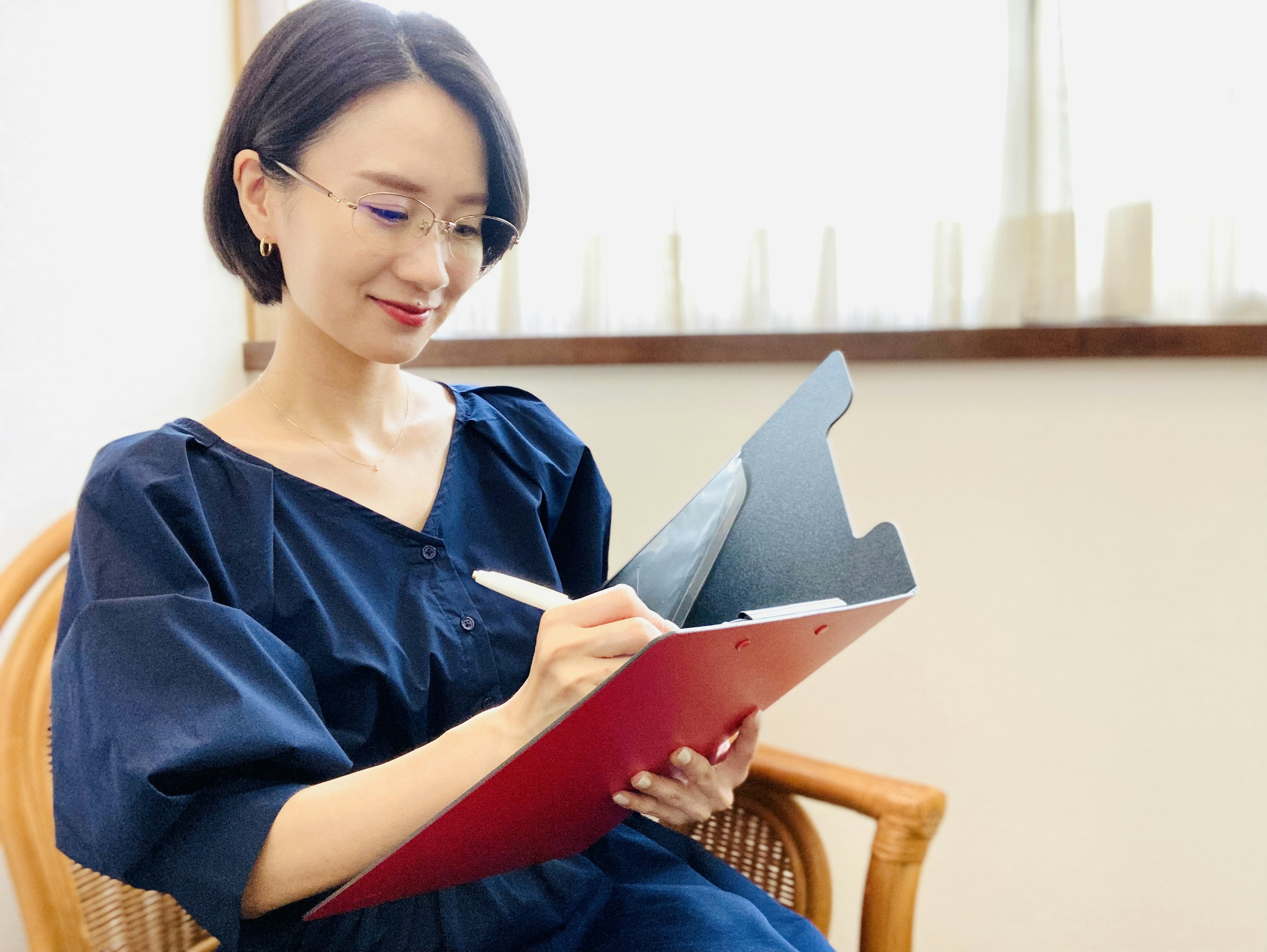 Una mujer sonriendo mientras escribe en un clipboard rojo en interiores