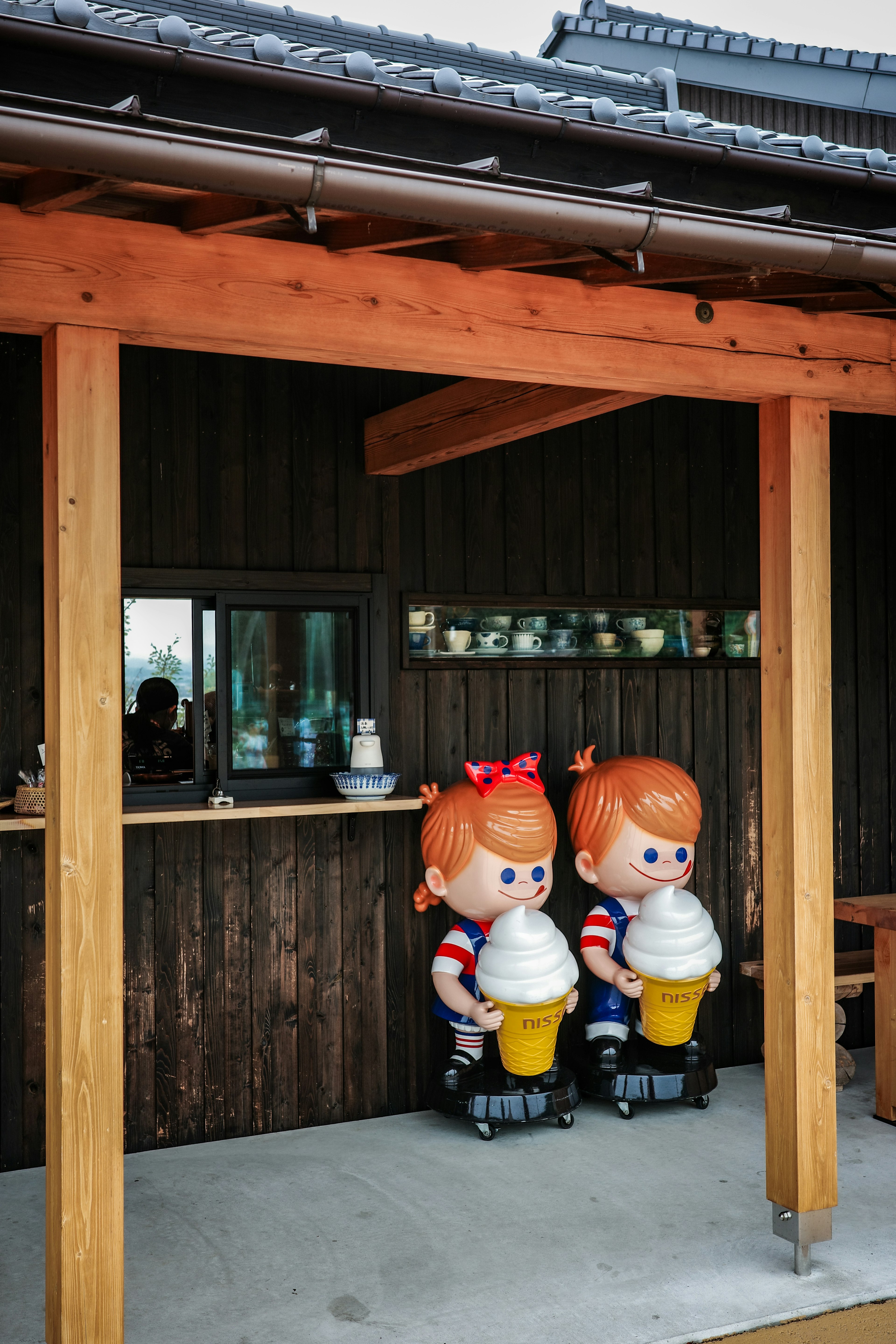 Zwei Kinderfiguren mit Eis vor einer kleinen Hütte